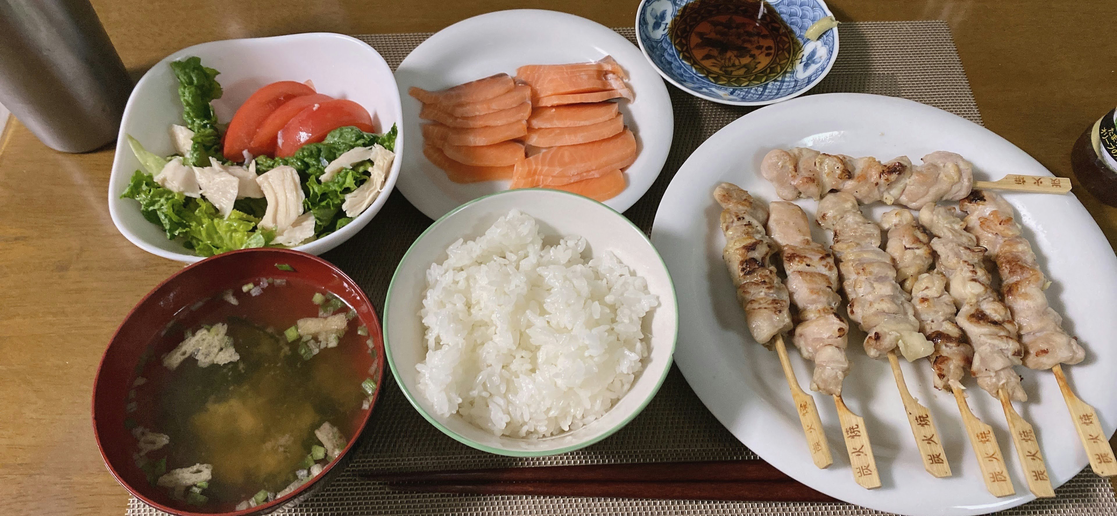 Xiên gà nướng, cơm trắng, súp miso, salad, cà chua, cà rốt trên đĩa