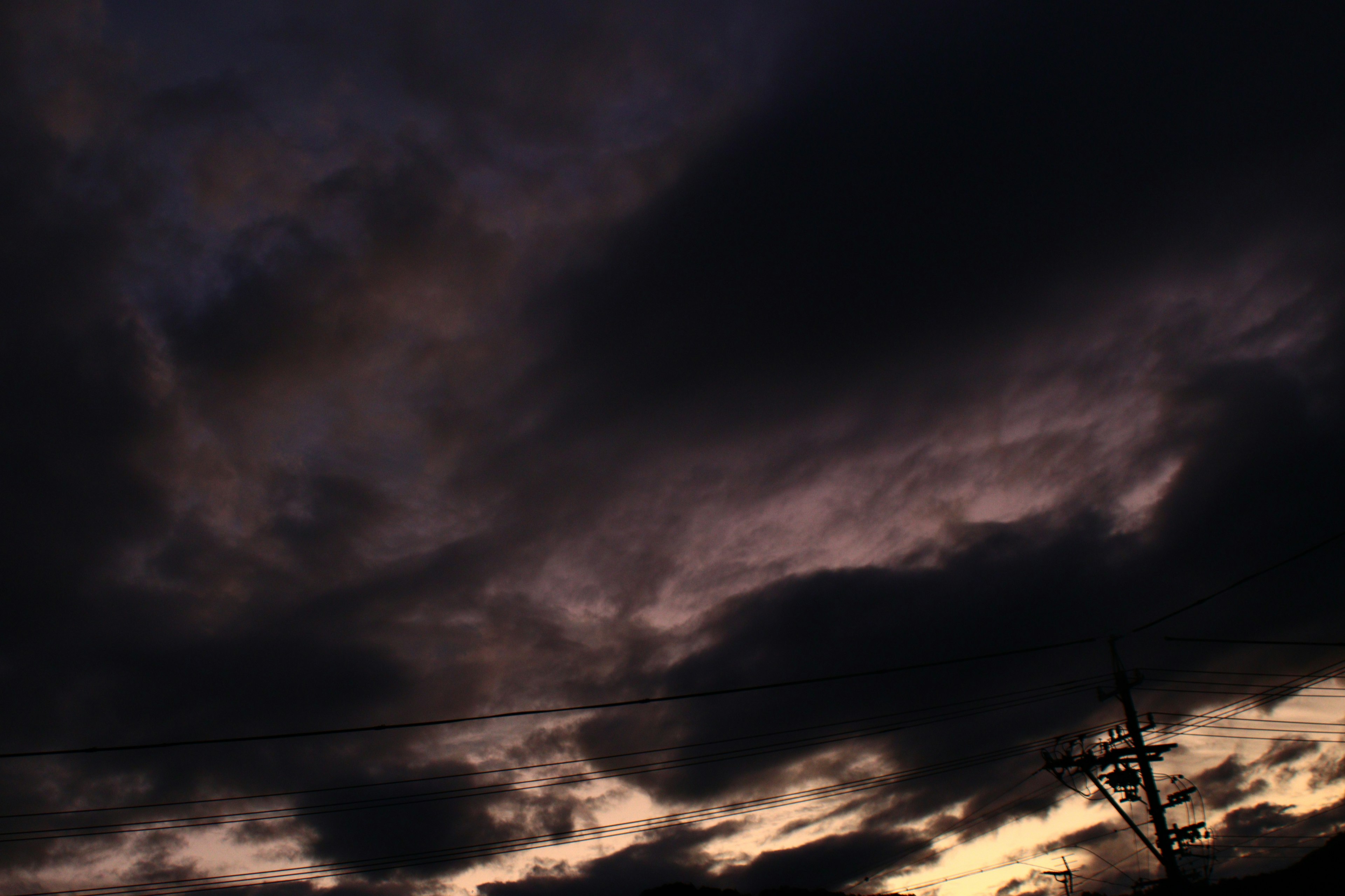 Dunkle Wolken bedecken den Himmel mit schwachem Sonnenunterganglicht