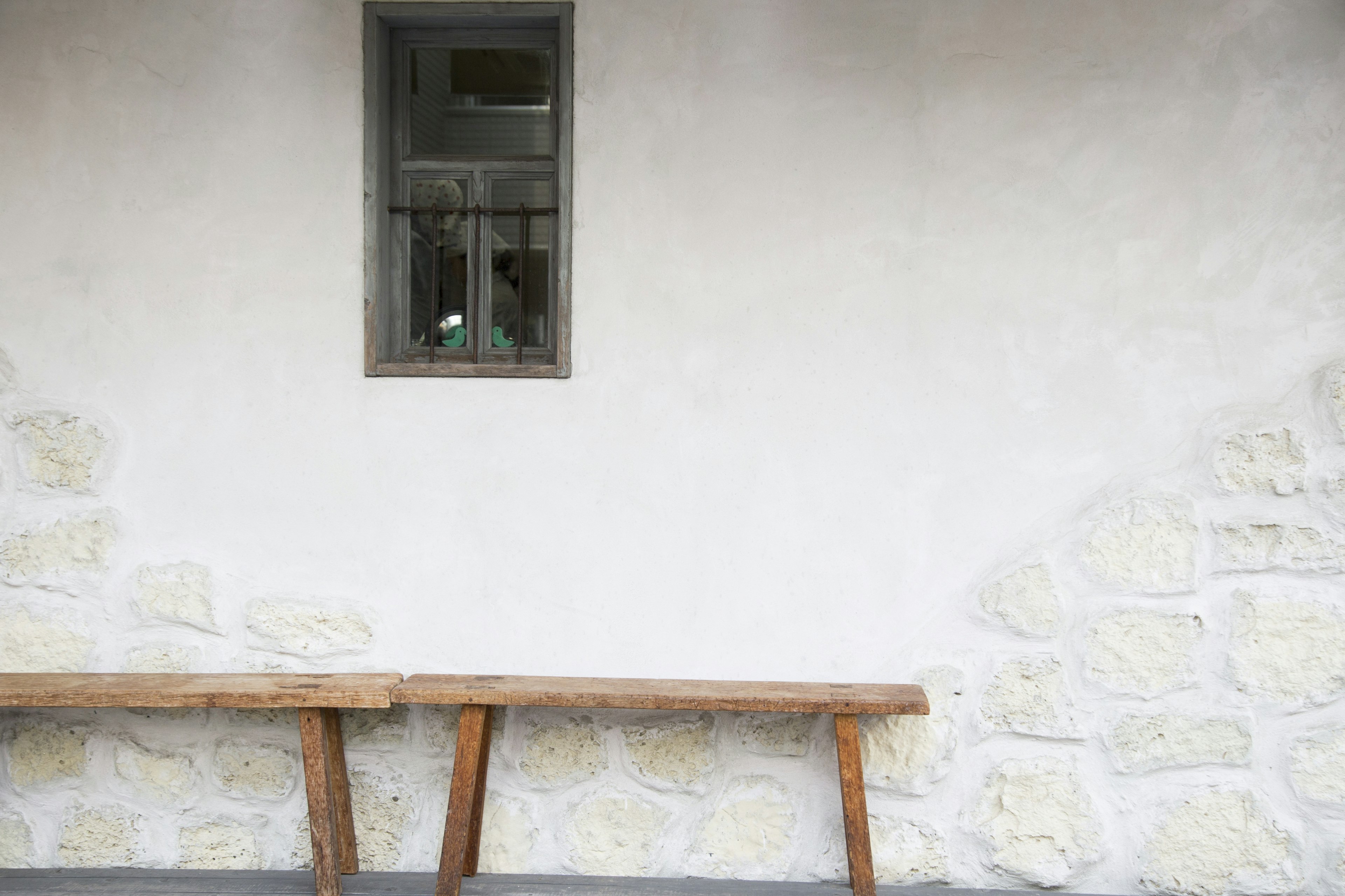 A simple exterior of a house featuring a stone wall and a wooden bench