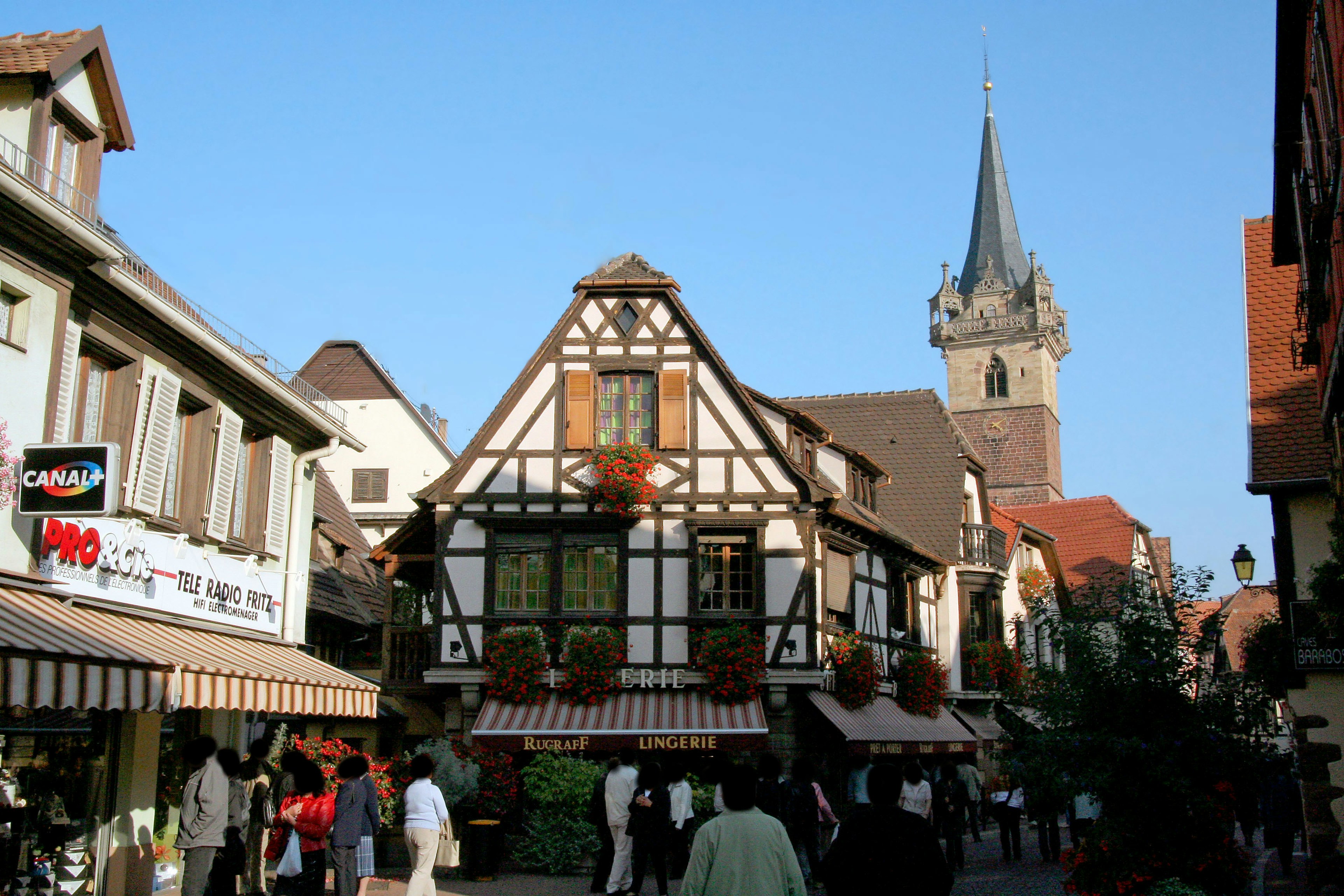 Traditional timber-framed buildings with a tower in a lively street scene