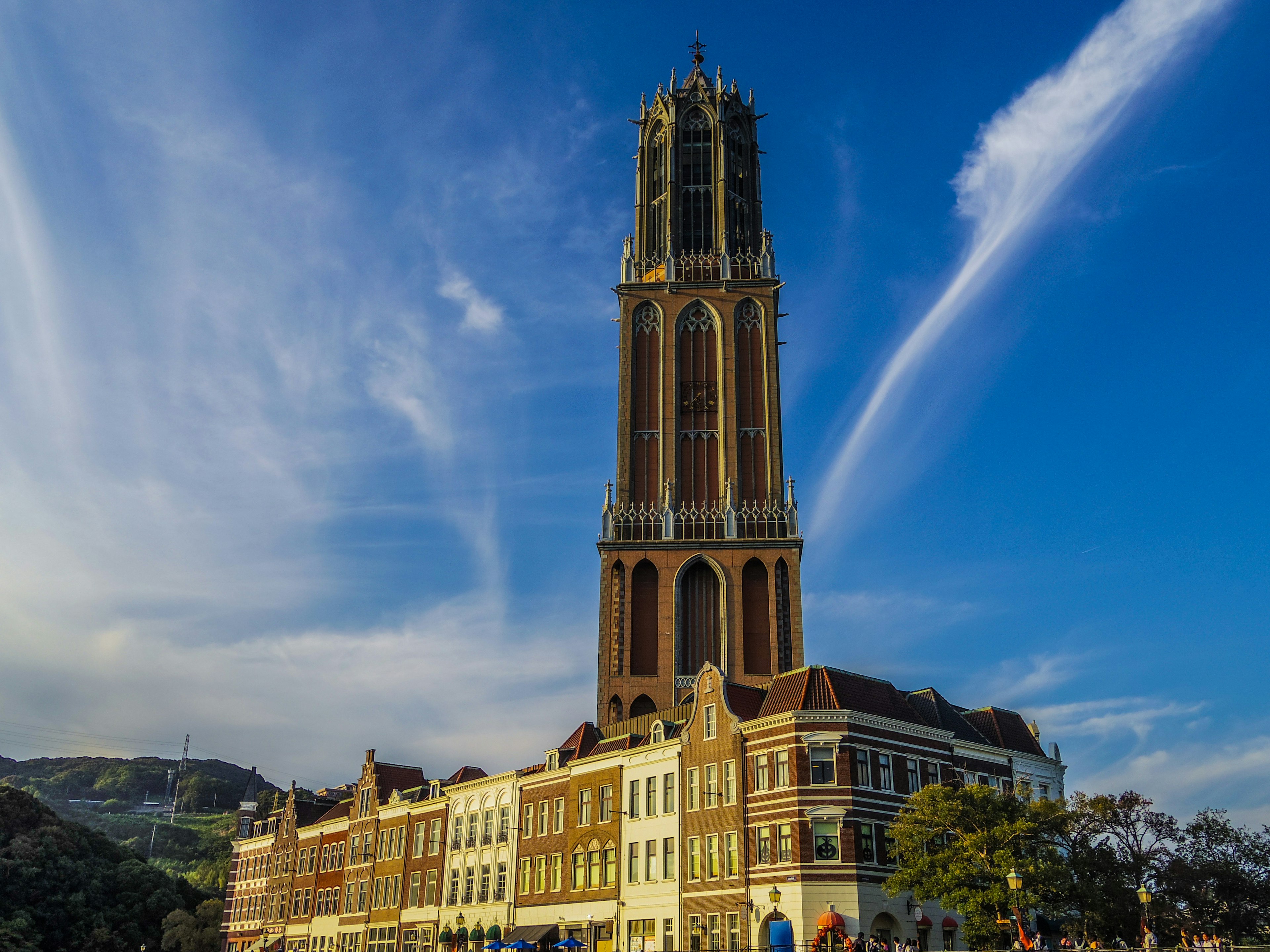 Tall clock tower under a blue sky with historic buildings in the foreground