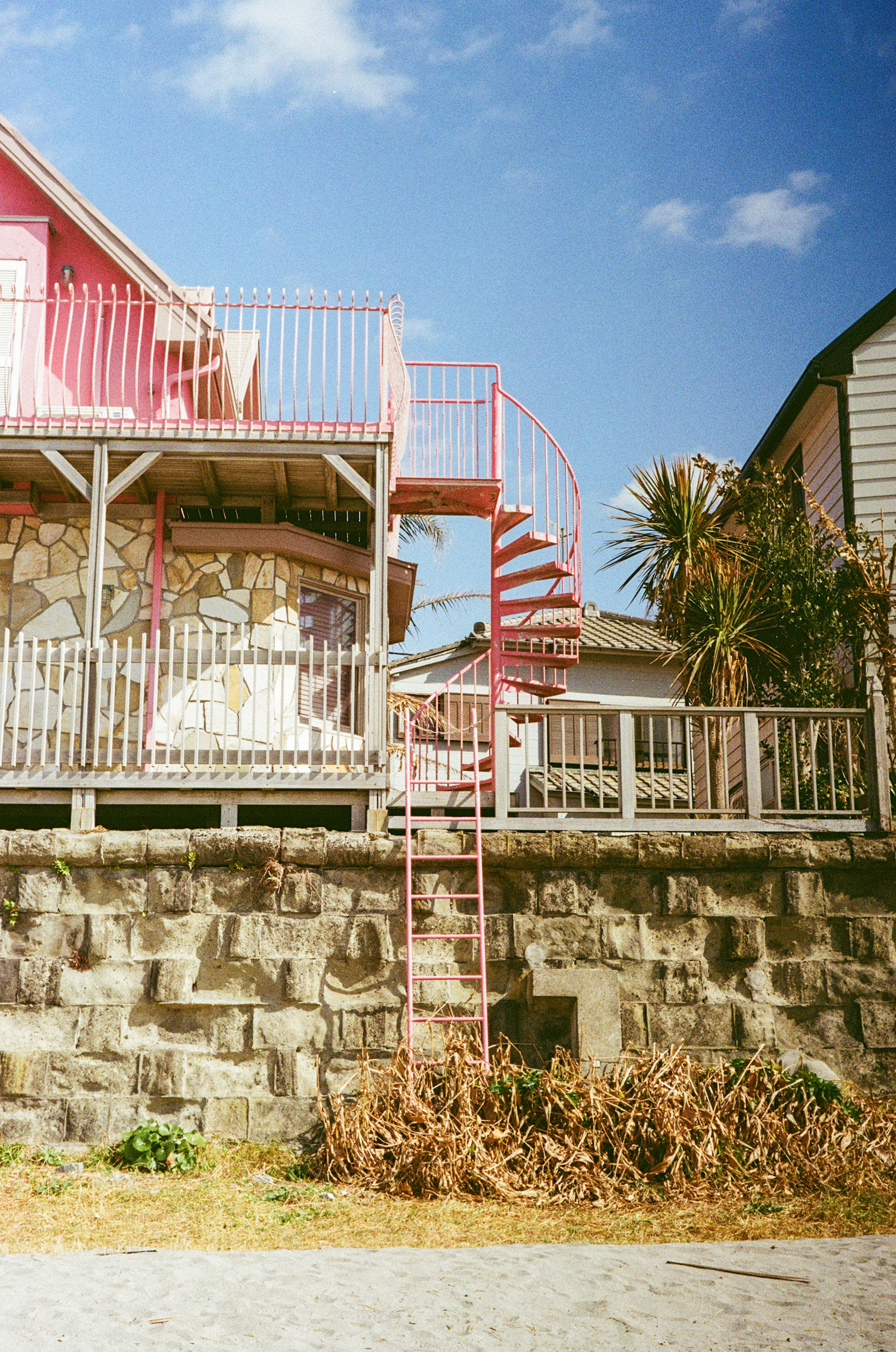 Vista exterior de una casa con una escalera de caracol rosa