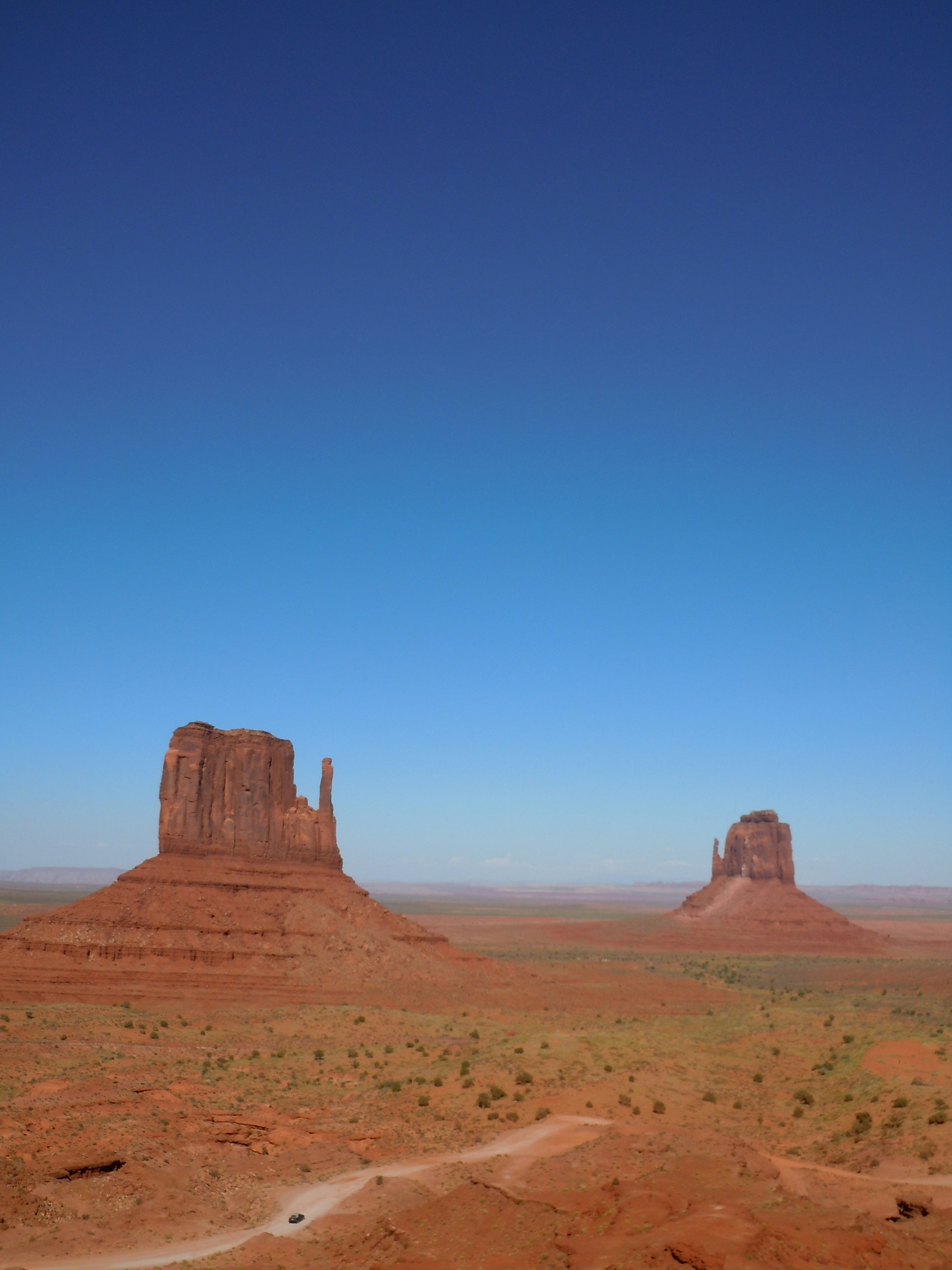 Pemandangan Monument Valley dengan formasi batu merah langit biru dan lahan luas