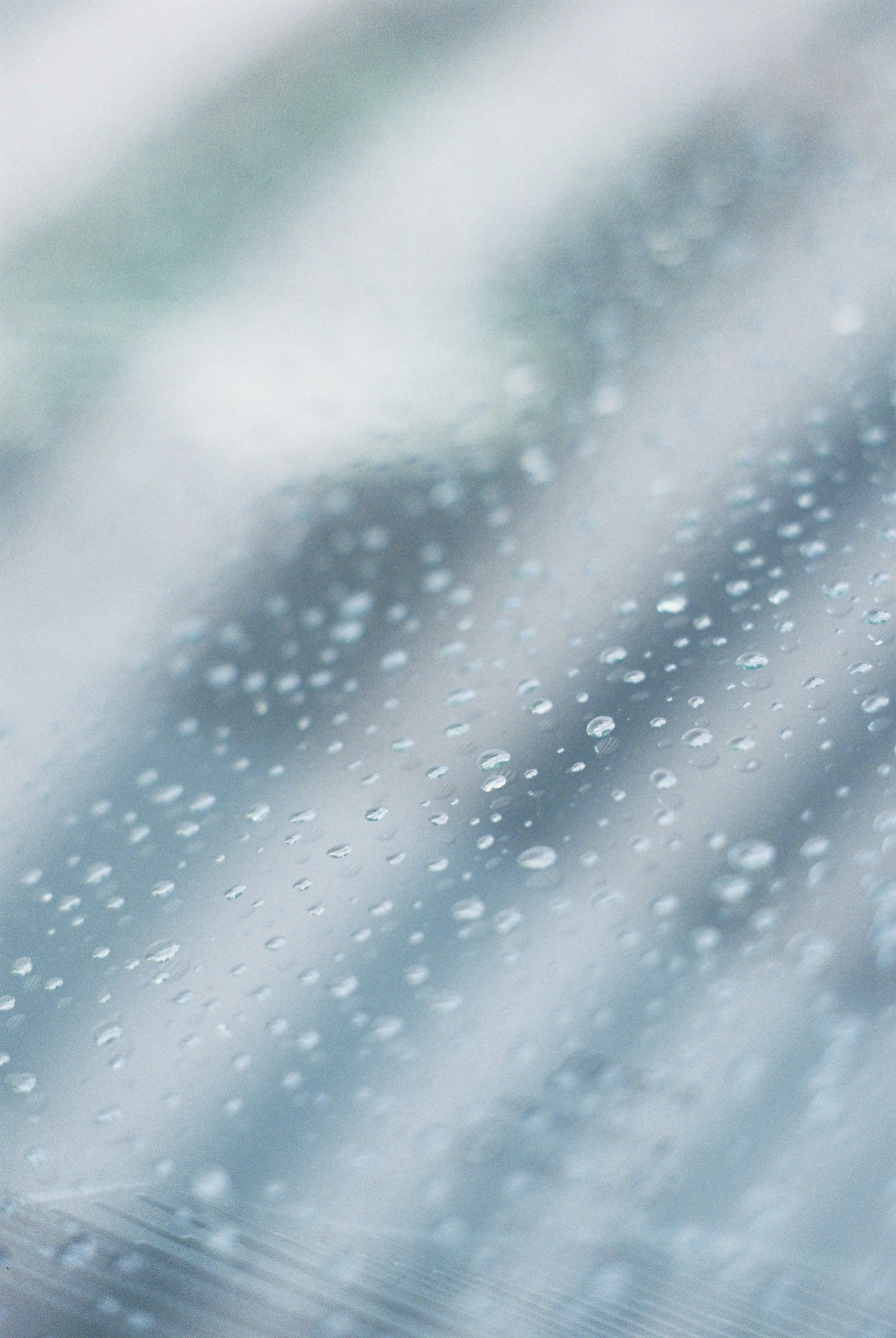 窗户上雨滴的特写，模糊的蓝色背景