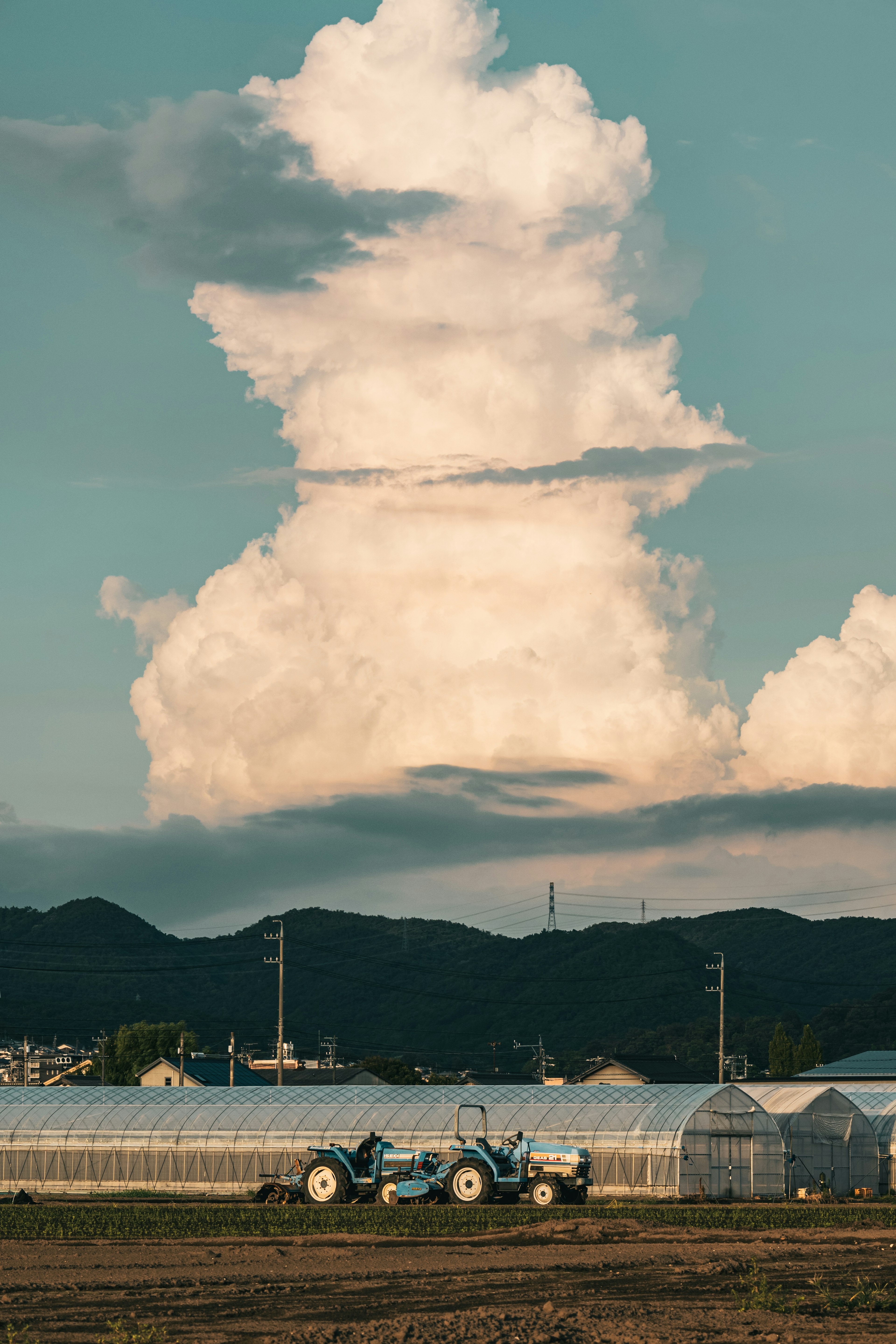 Ein blauer Traktor unter einer großen Wolke in einer ländlichen Landschaft