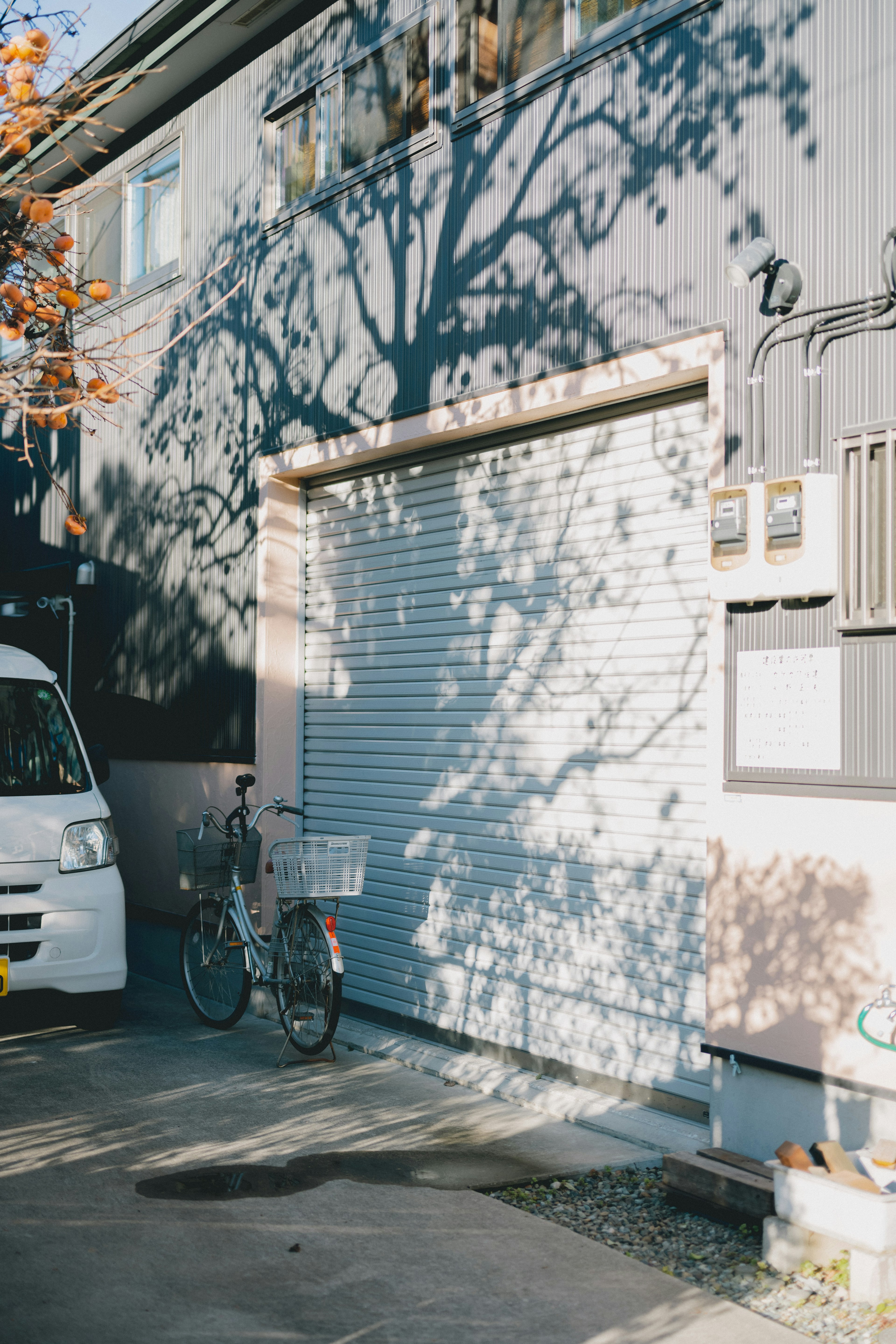 Ein Fahrrad steht vor einem Rollladen mit Schatten an der Wand