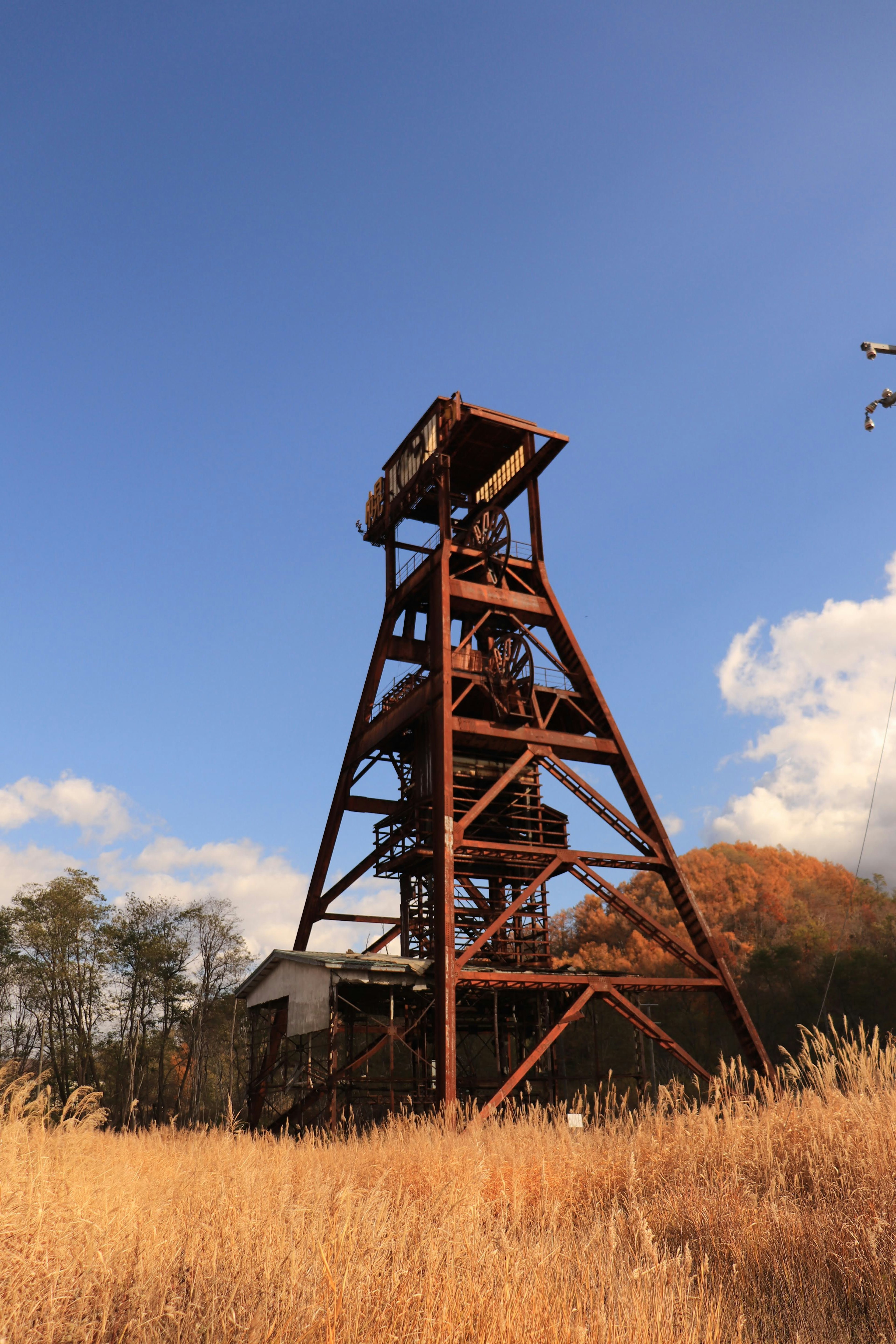 A tall metal tower stands under a blue sky surrounded by grass