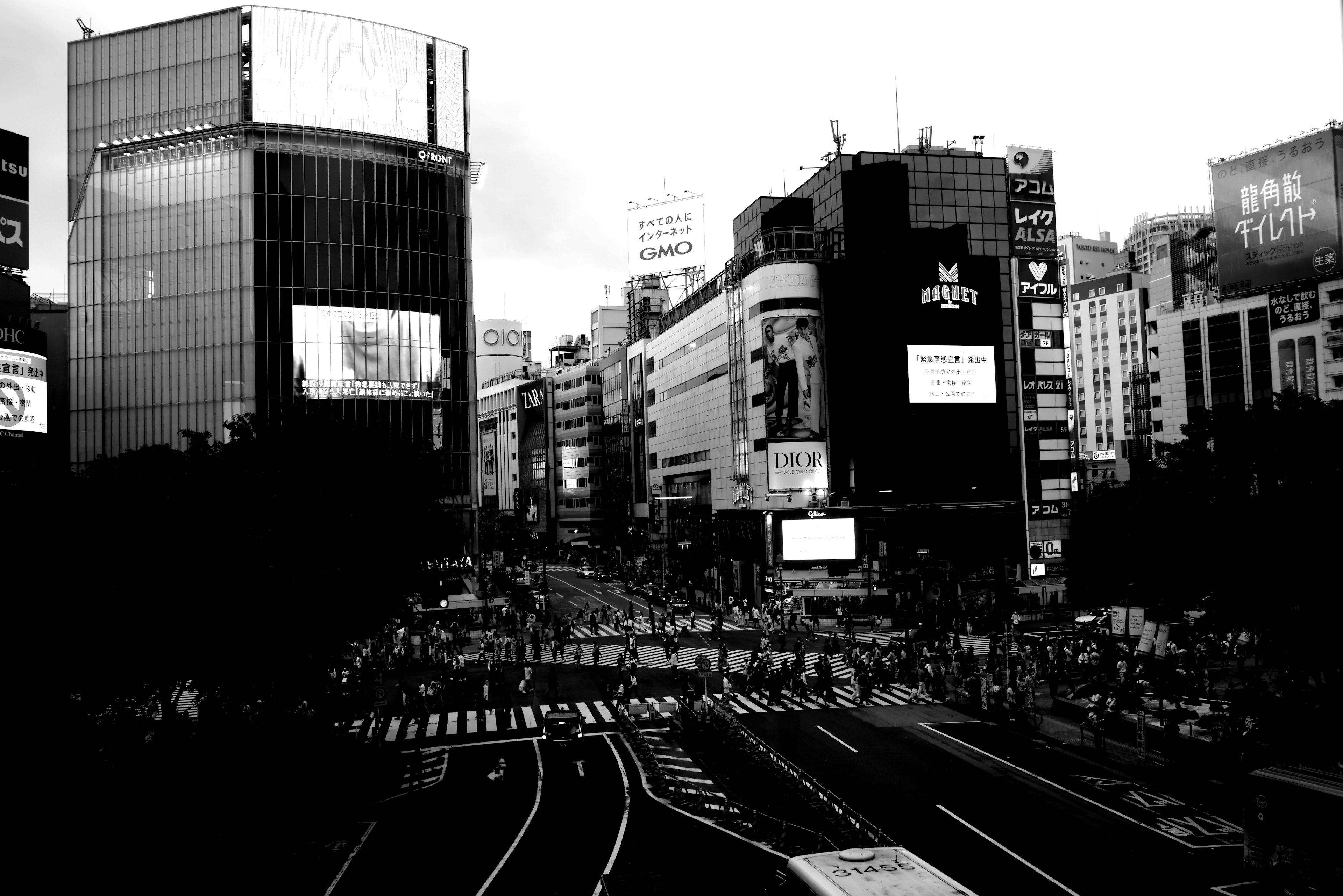 Imagen en blanco y negro de las bulliciosas calles de Tokio con grandes edificios y una intersección concurrida