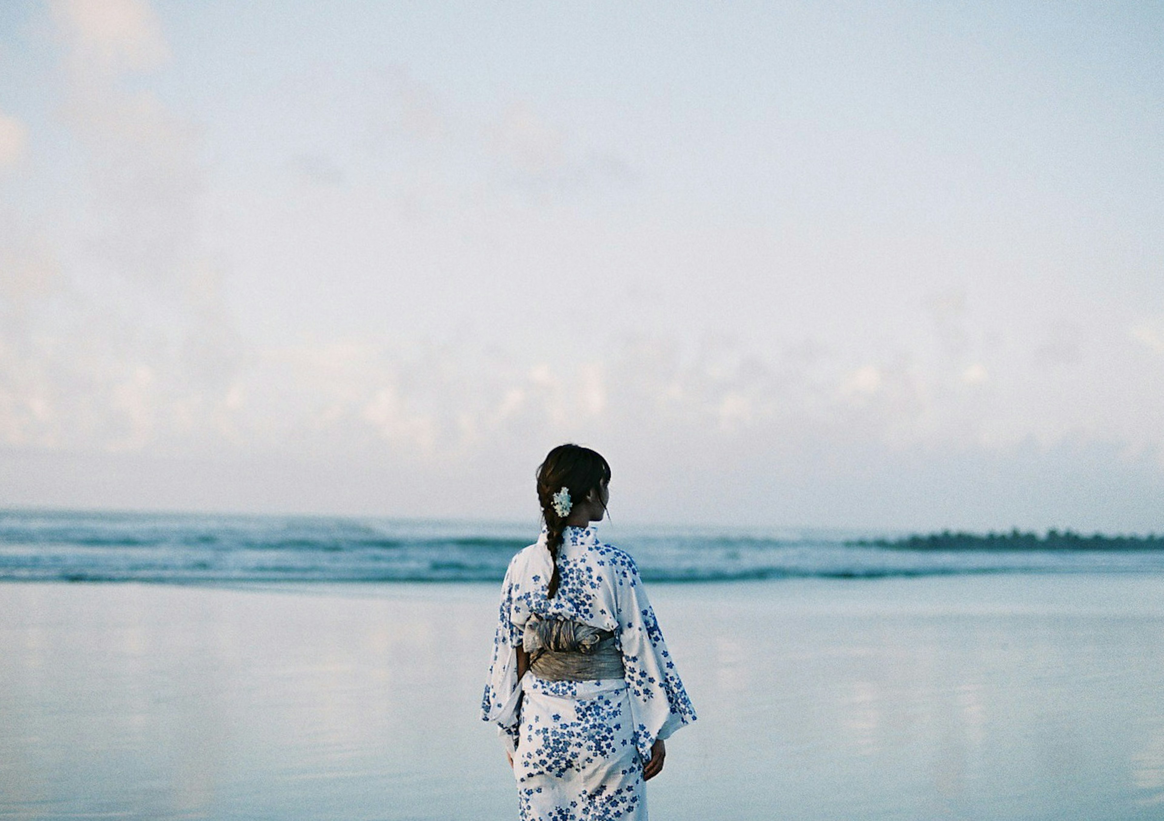 穿白色裙子的女人在海滩上回望海洋