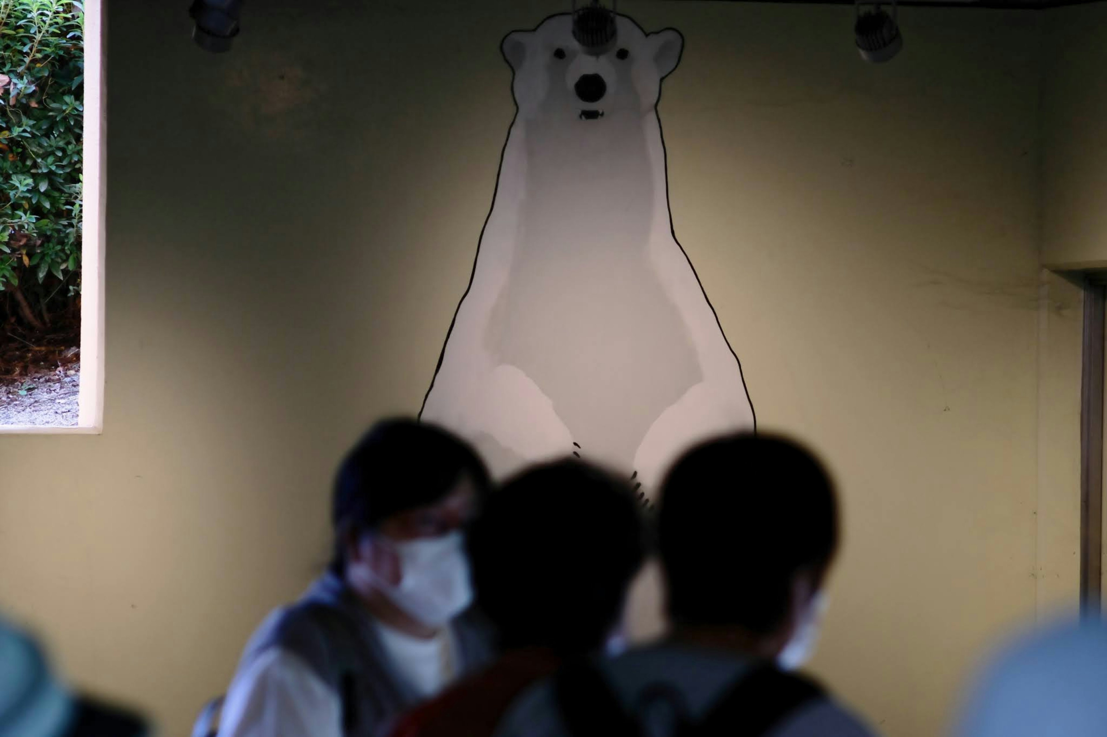 Des personnes portant des masques devant un mur avec une illustration d'ours polaire