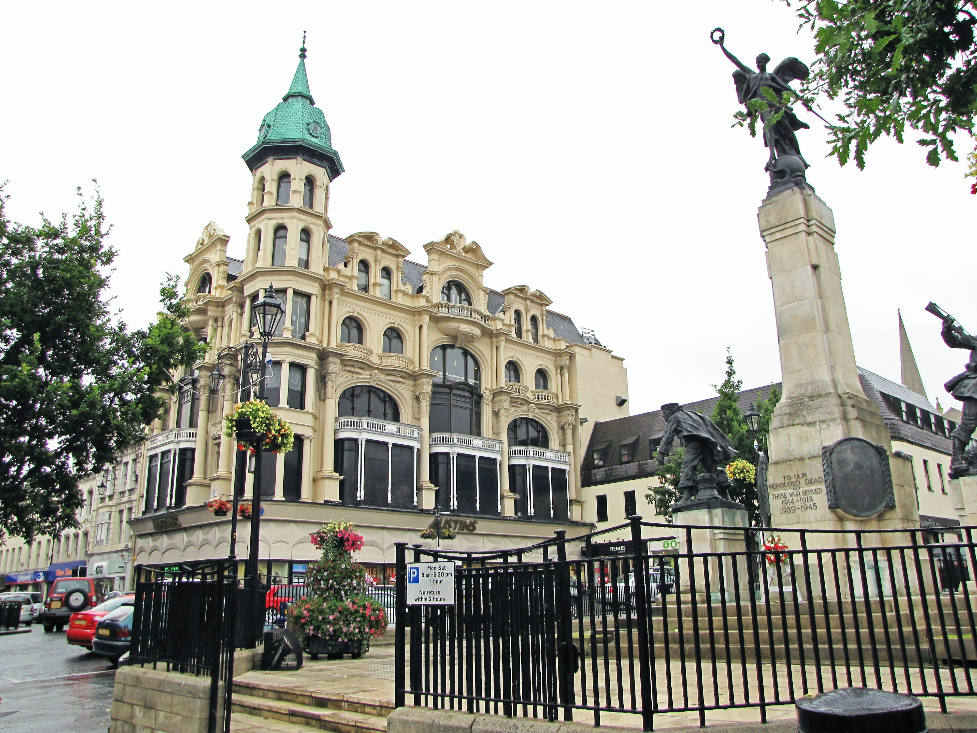 A beautiful building with a green dome and a monument in a town square