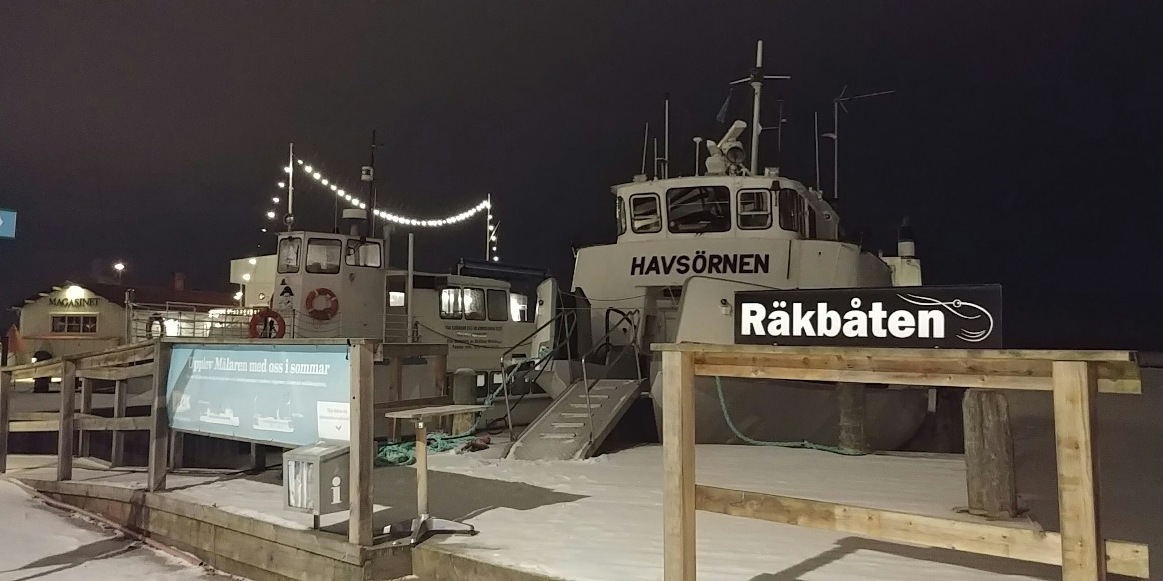 Escena nocturna de un barco amarrado con un cartel en el puerto