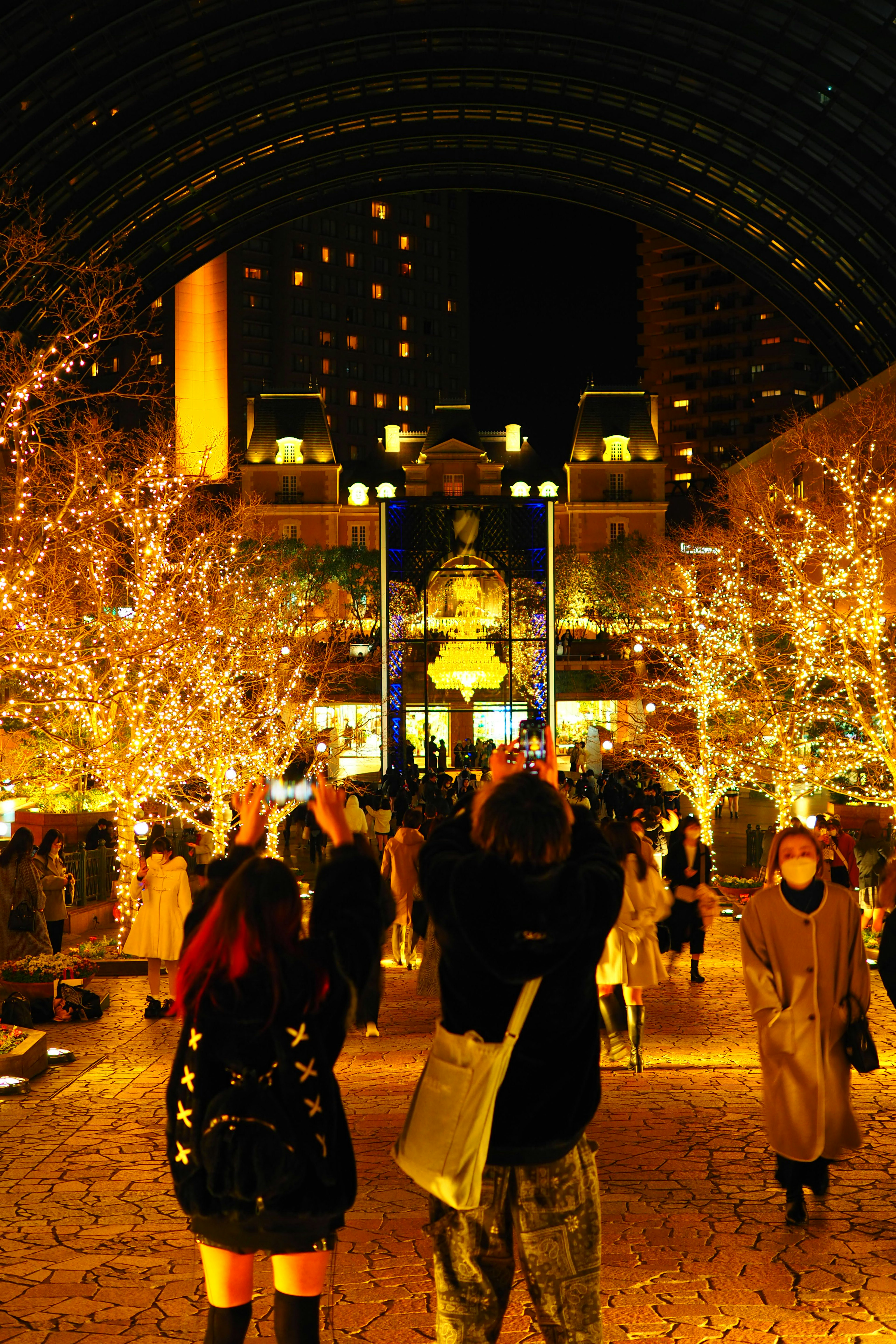 夜の街の光に包まれた人々とイルミネーションの木々