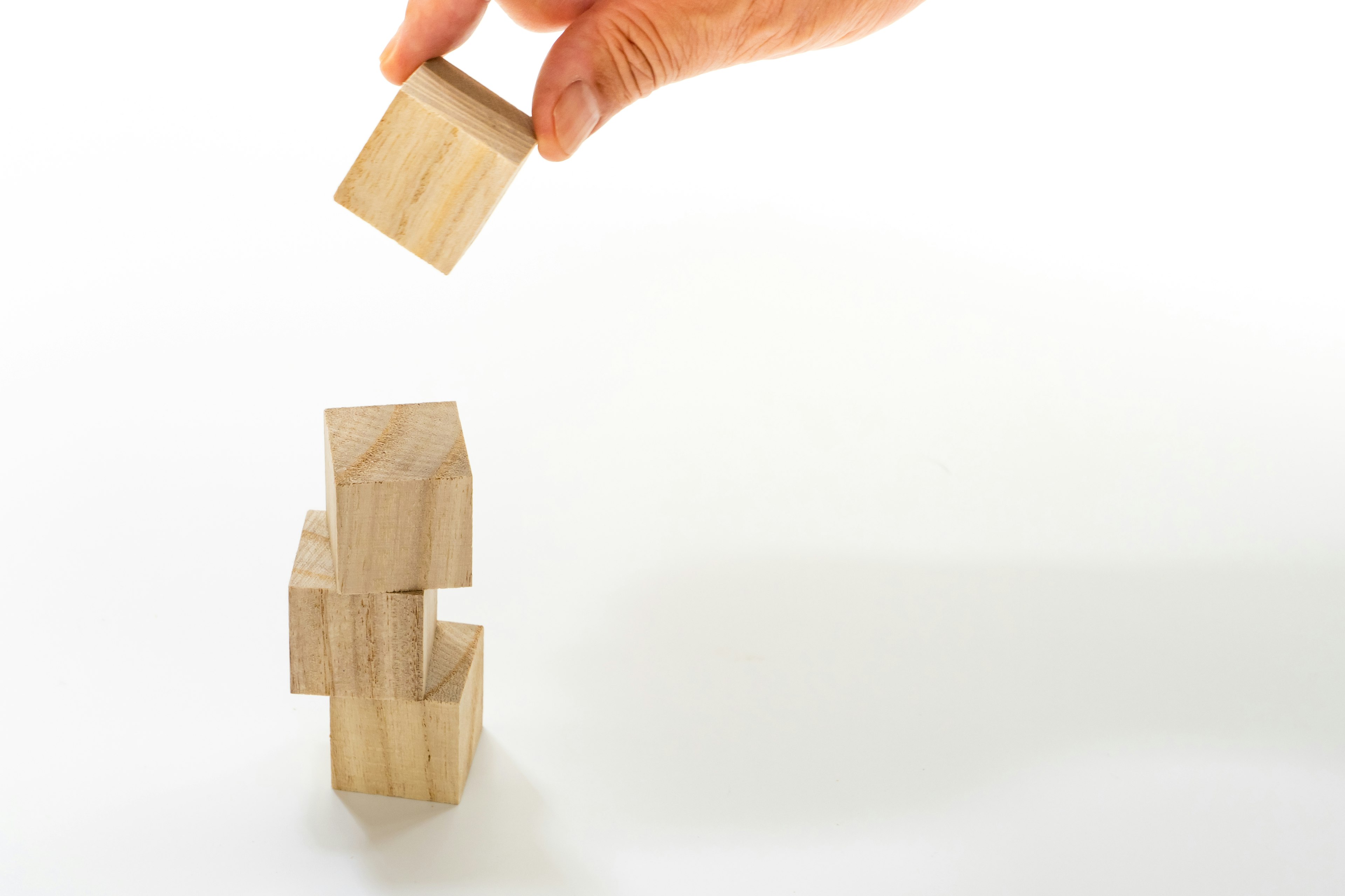 Main plaçant un bloc en bois sur une pile