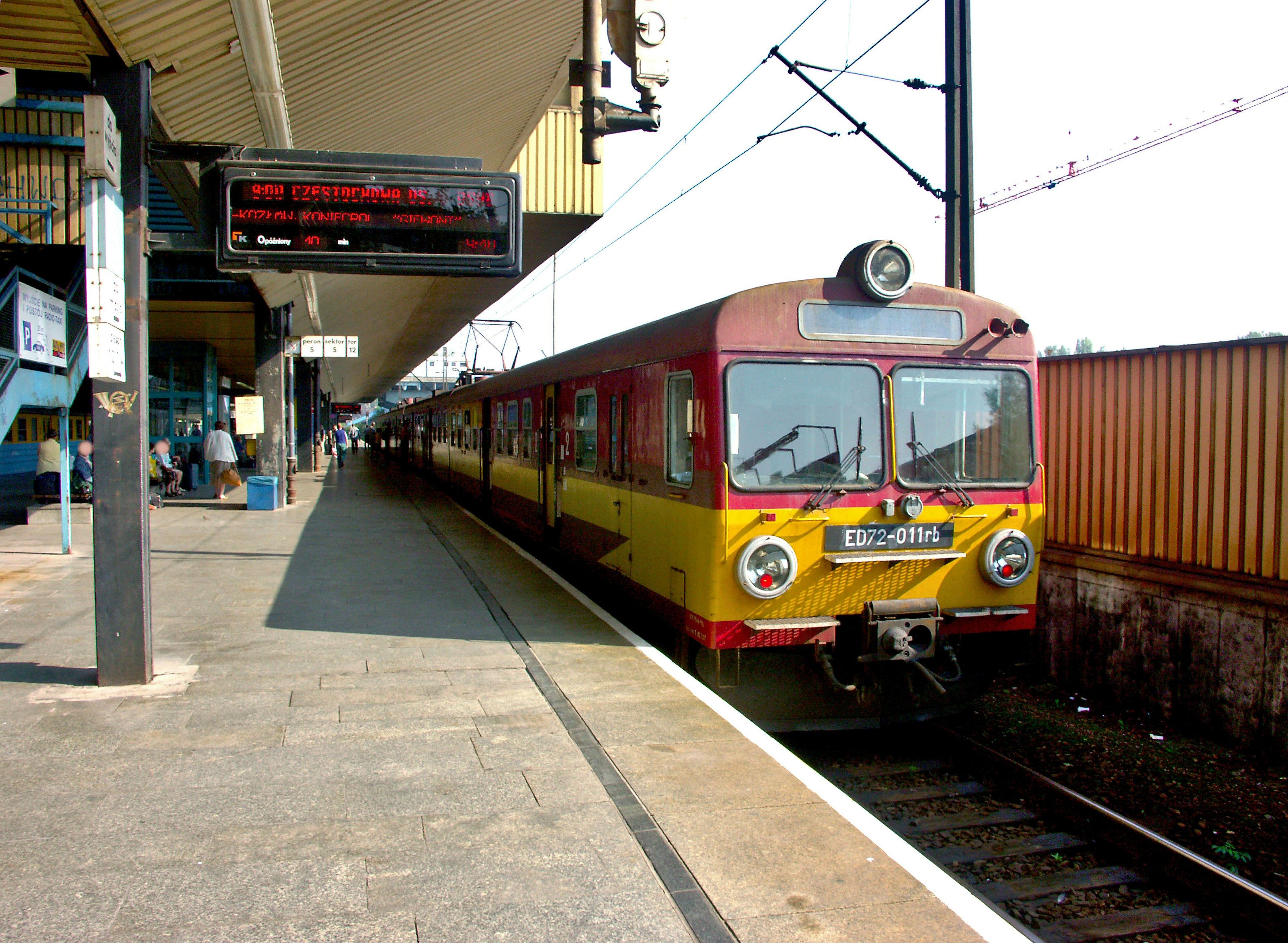 Colorful train at a station with a visible platform and electronic display