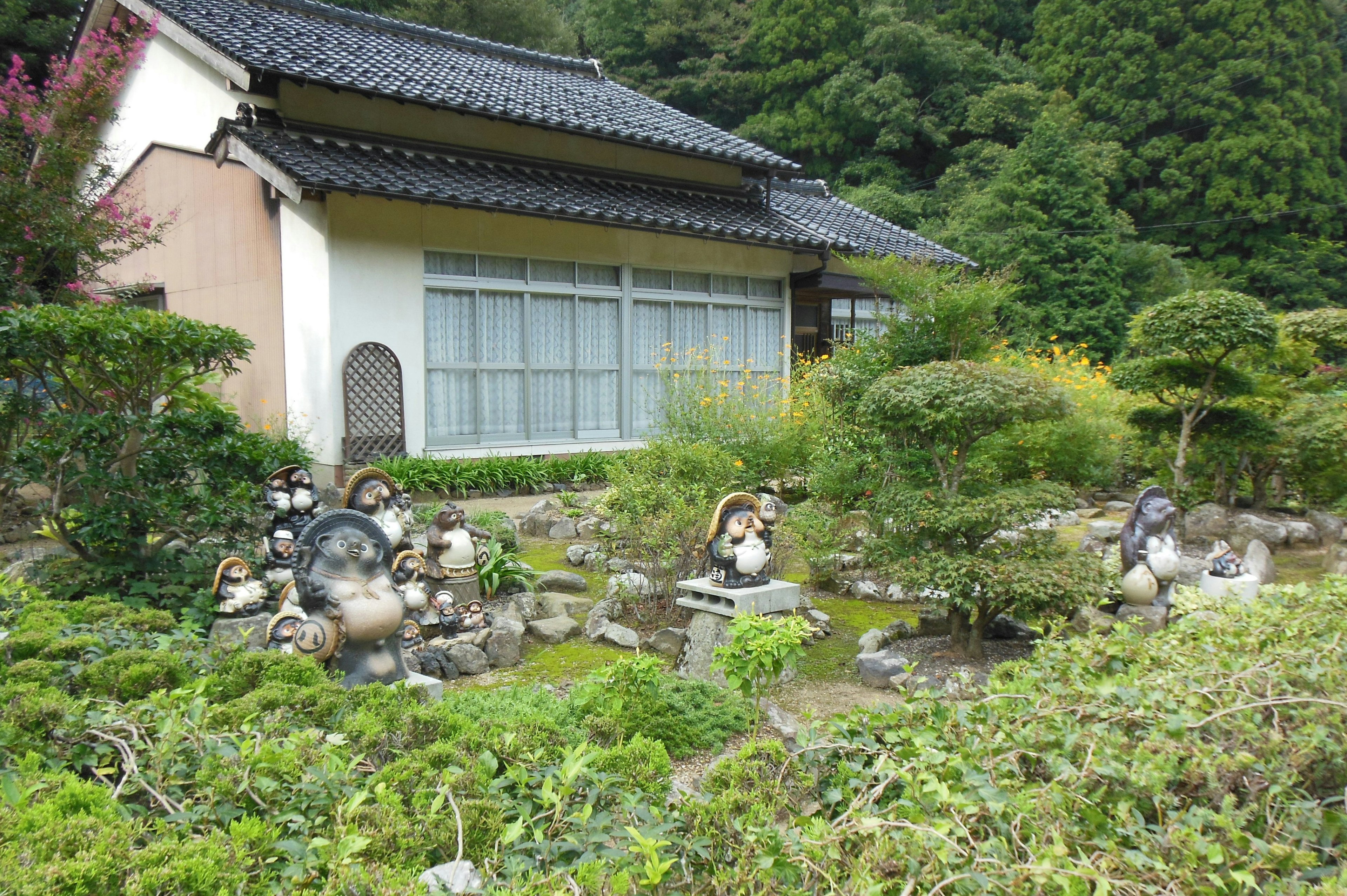 Traditional Japanese house surrounded by a lush garden and stone sculptures