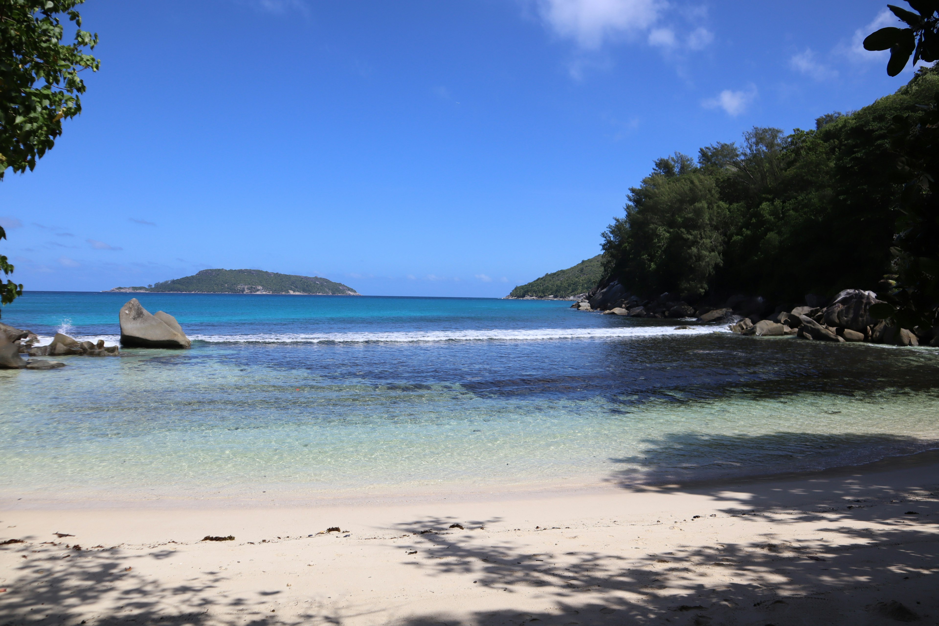 Scenic beach with clear blue water green trees and rocky formations