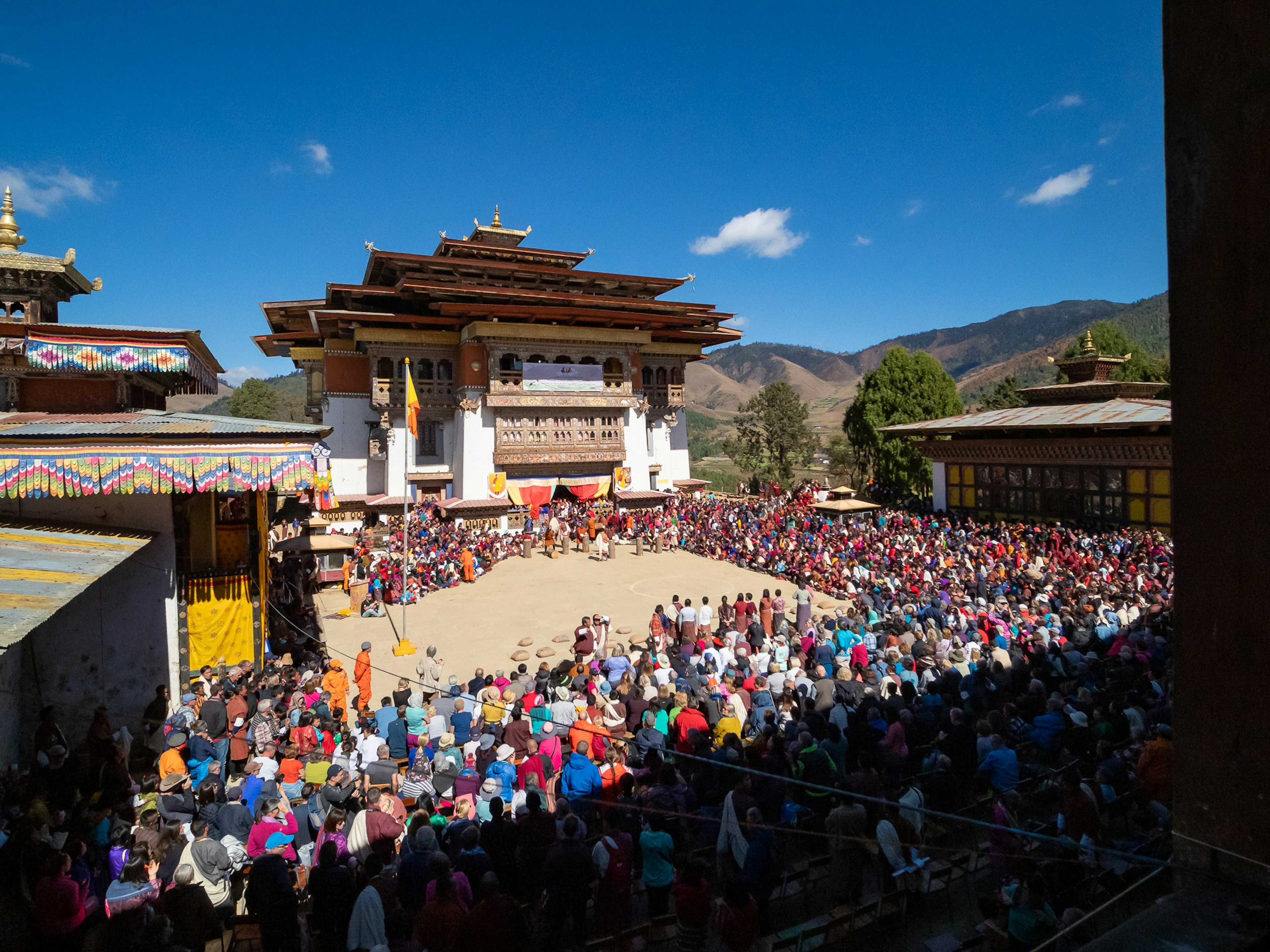 Adegan hidup festival tradisional Bhutan dengan banyak orang berkumpul di sekitar bangunan megah