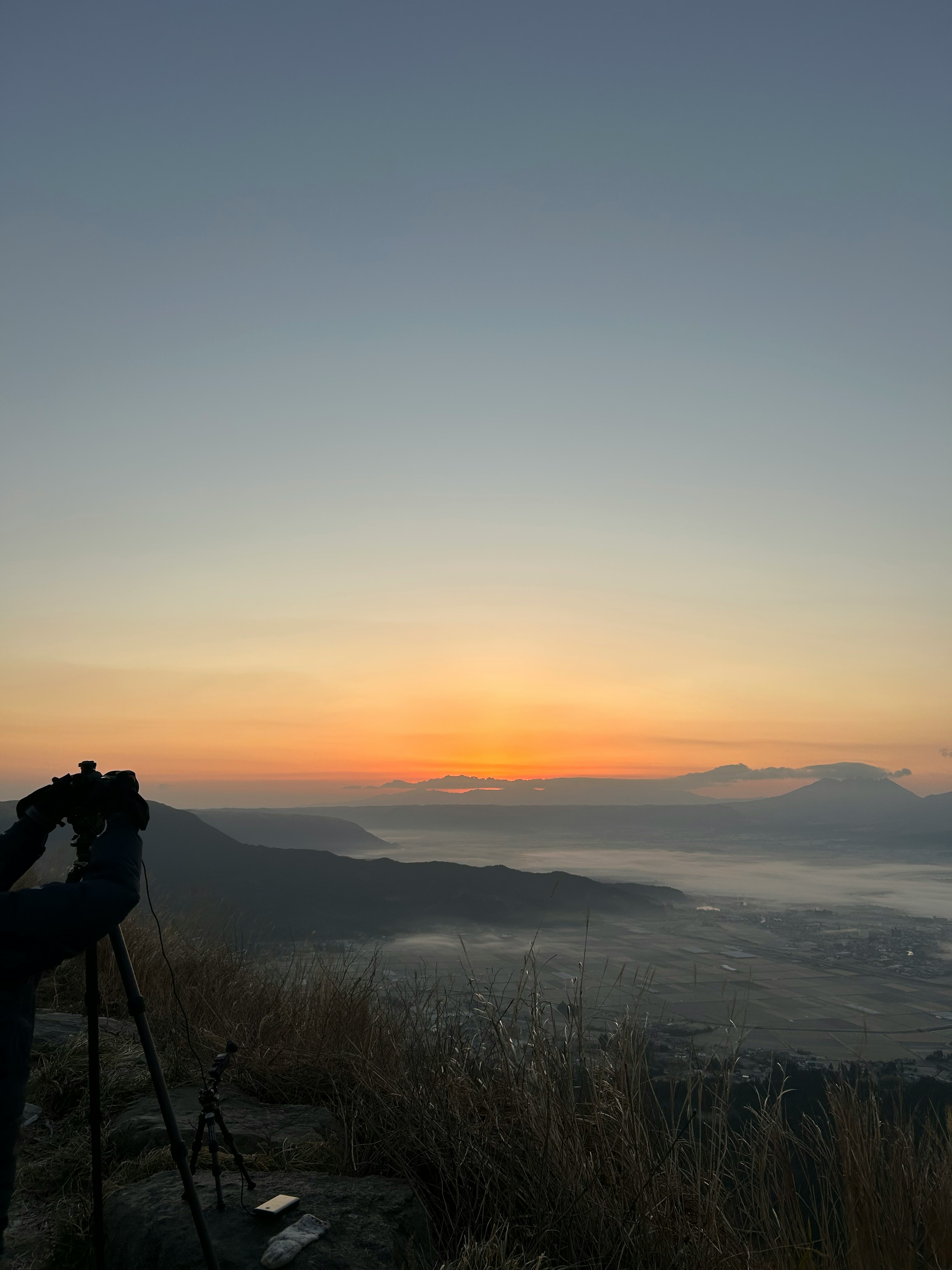 Silhouette eines Fotografen, der den Sonnenuntergang von einem Berggipfel aufnimmt