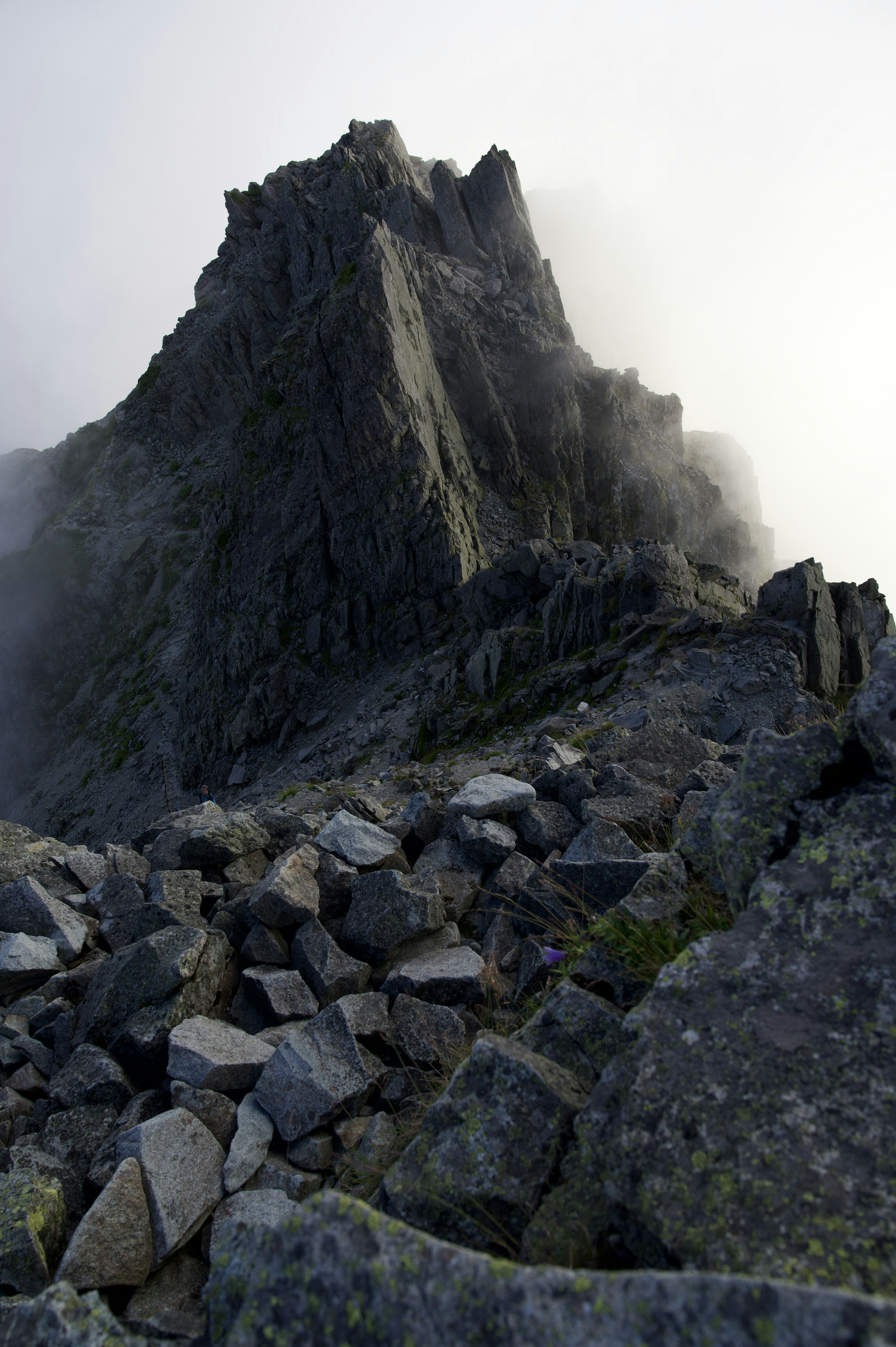 Pico de montaña afilado envuelto en niebla con terreno rocoso