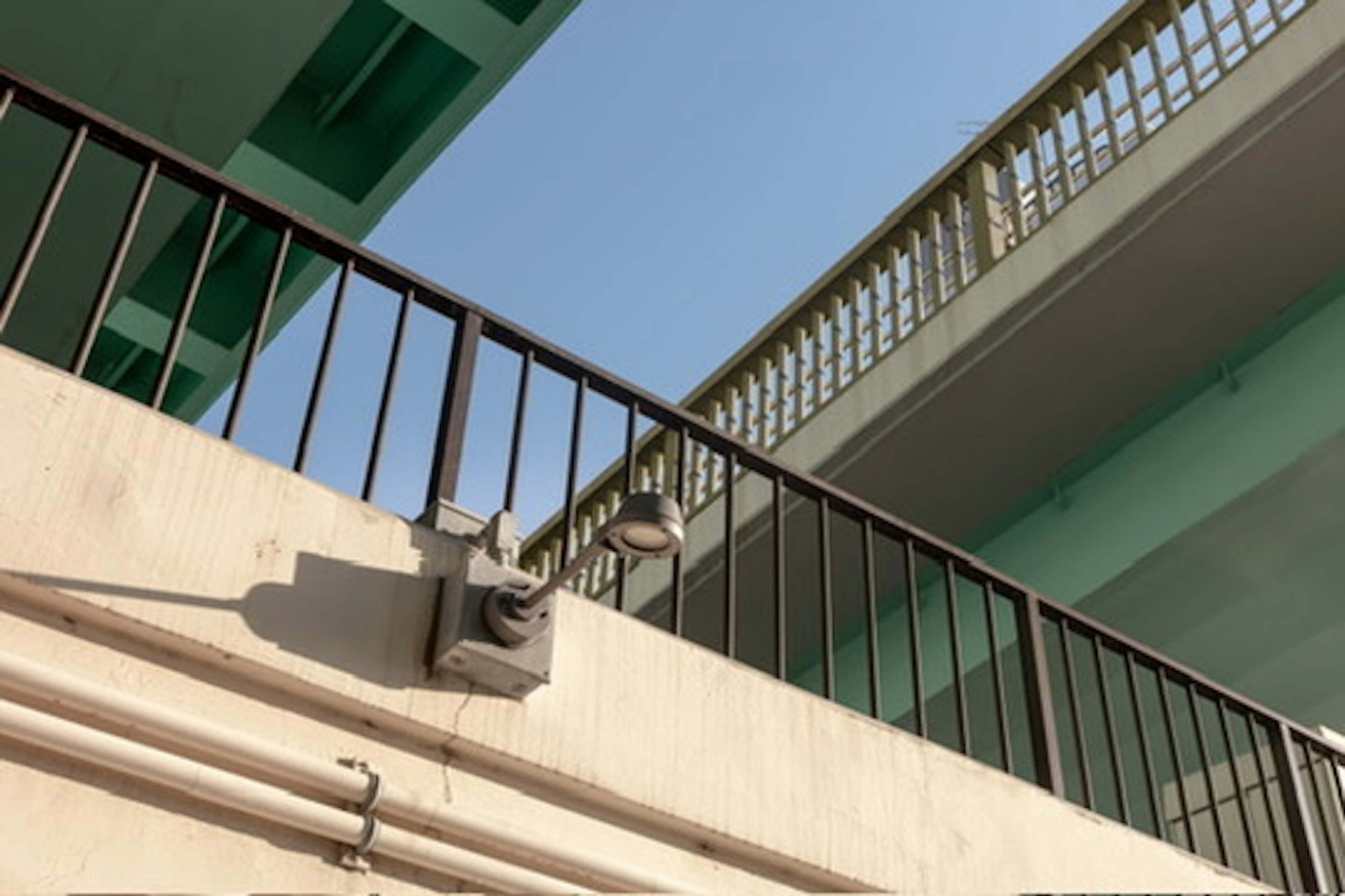 Photo of a two-story building balcony and railing under a blue sky