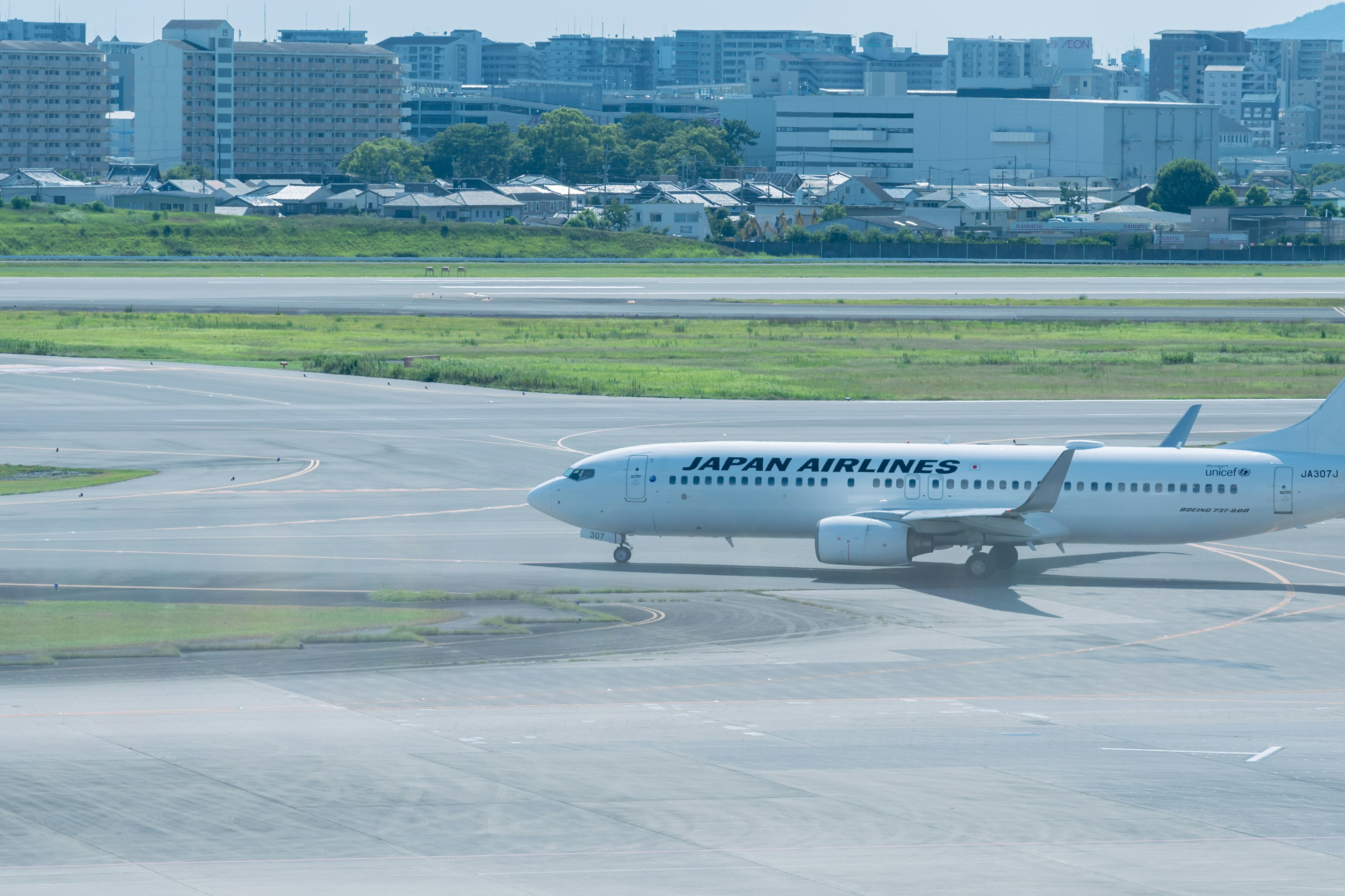 空港の滑走路でタクシー中の航空機と背景の都市景観