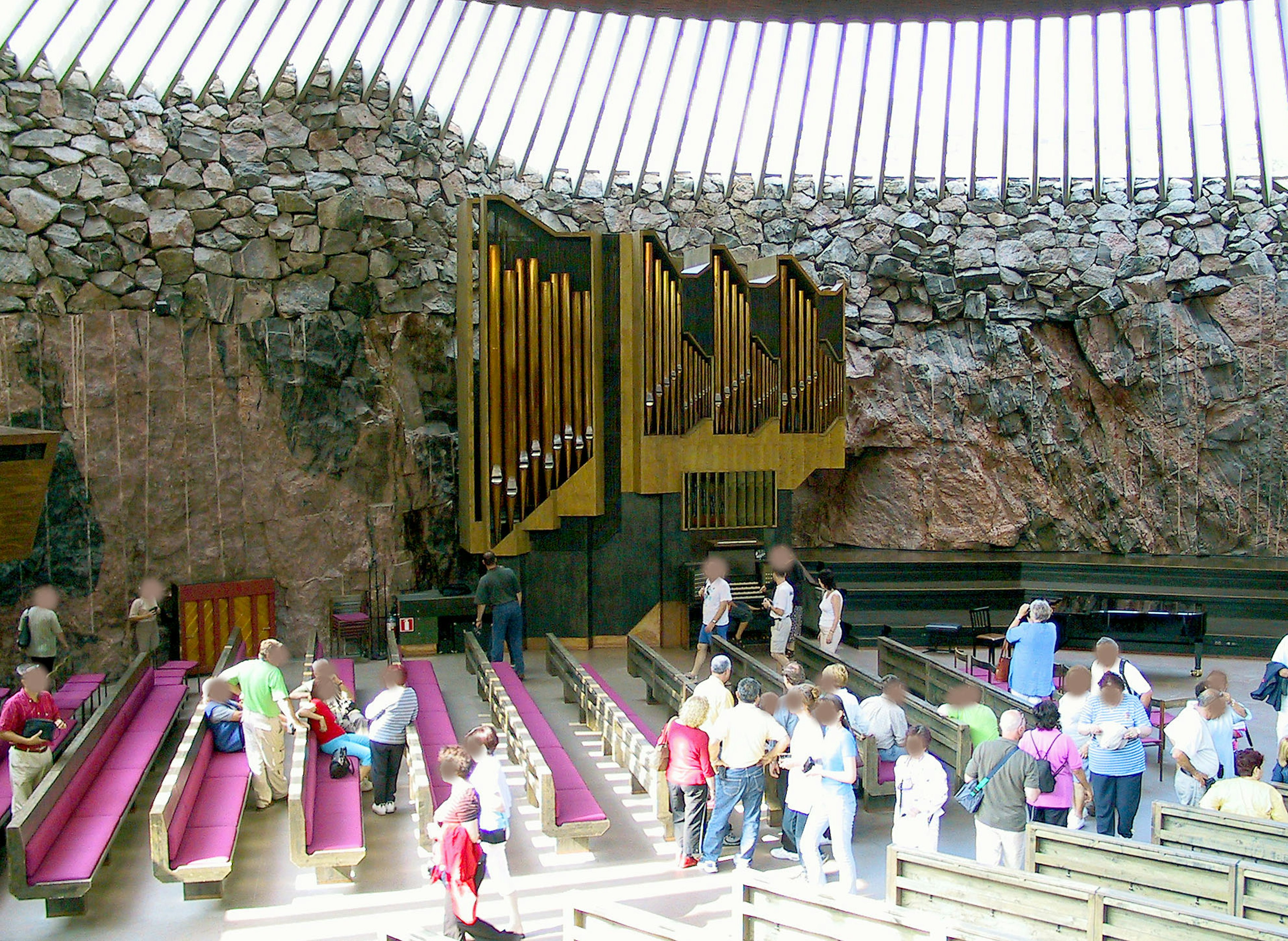 Interior gereja Temppeliaukio di Helsinki dengan dinding batu dan bangku kayu