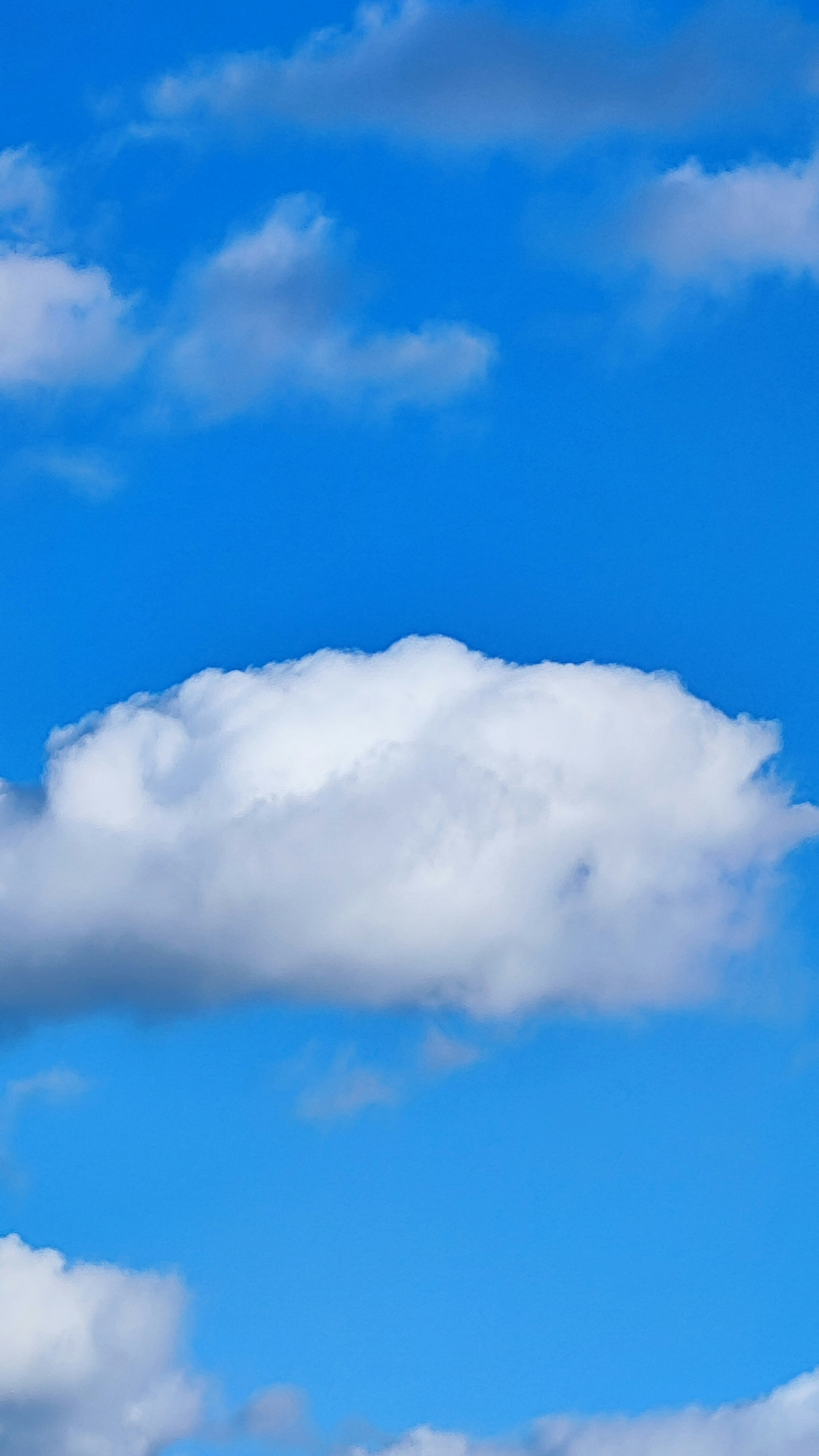 Eine Landschaft mit weißen Wolken, die in einem blauen Himmel schweben