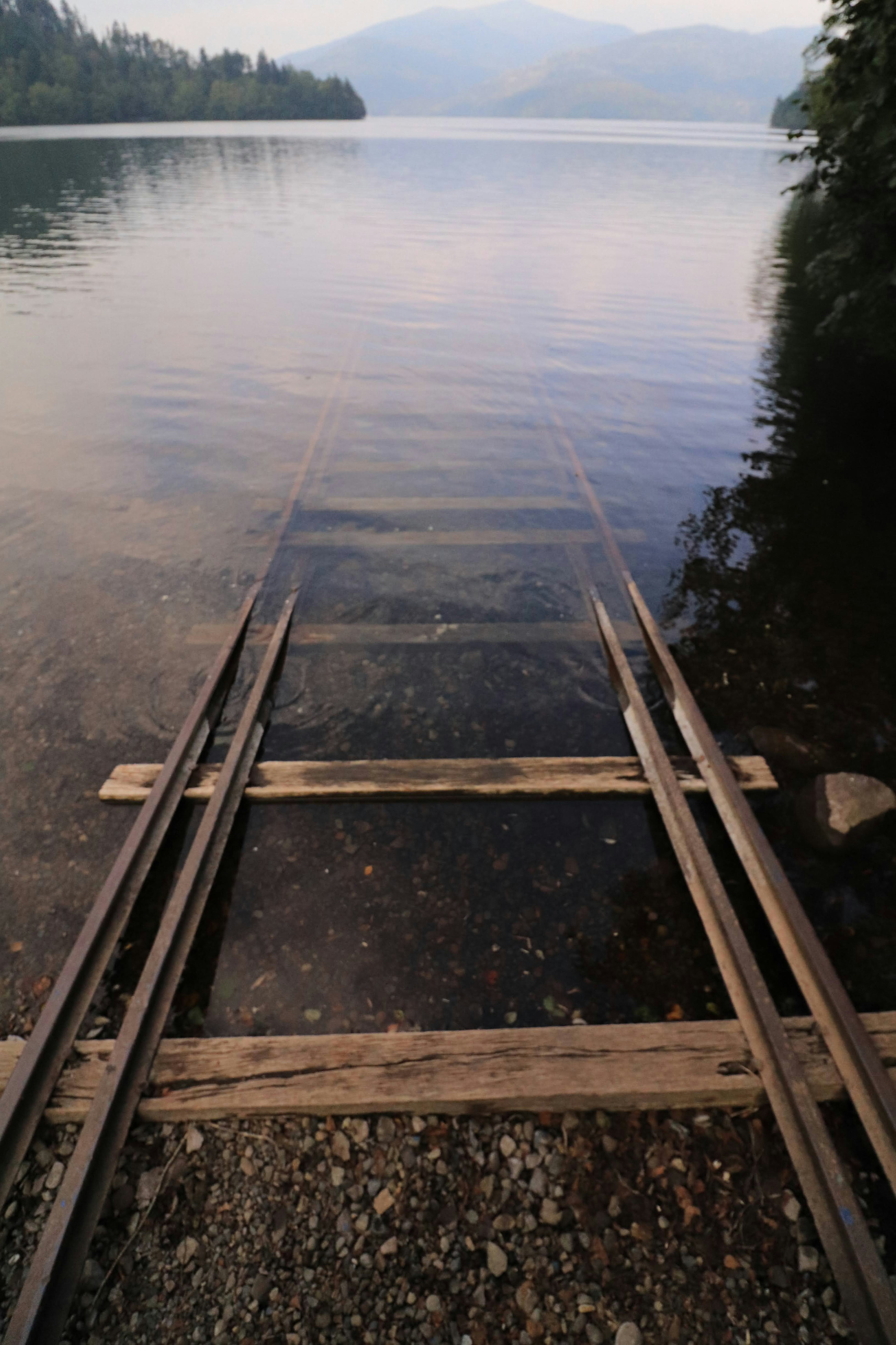 Rel kereta kayu yang membentang ke danau tenang