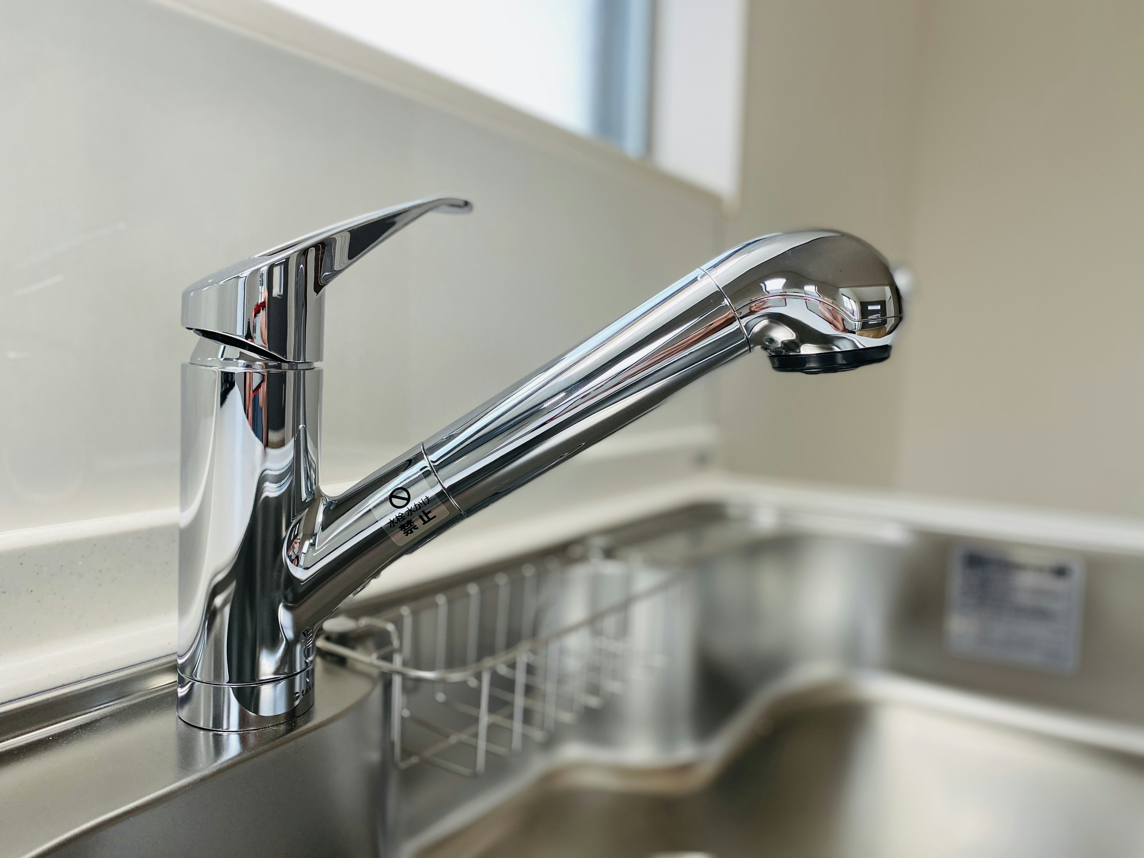 Shiny chrome kitchen faucet near a stainless steel sink