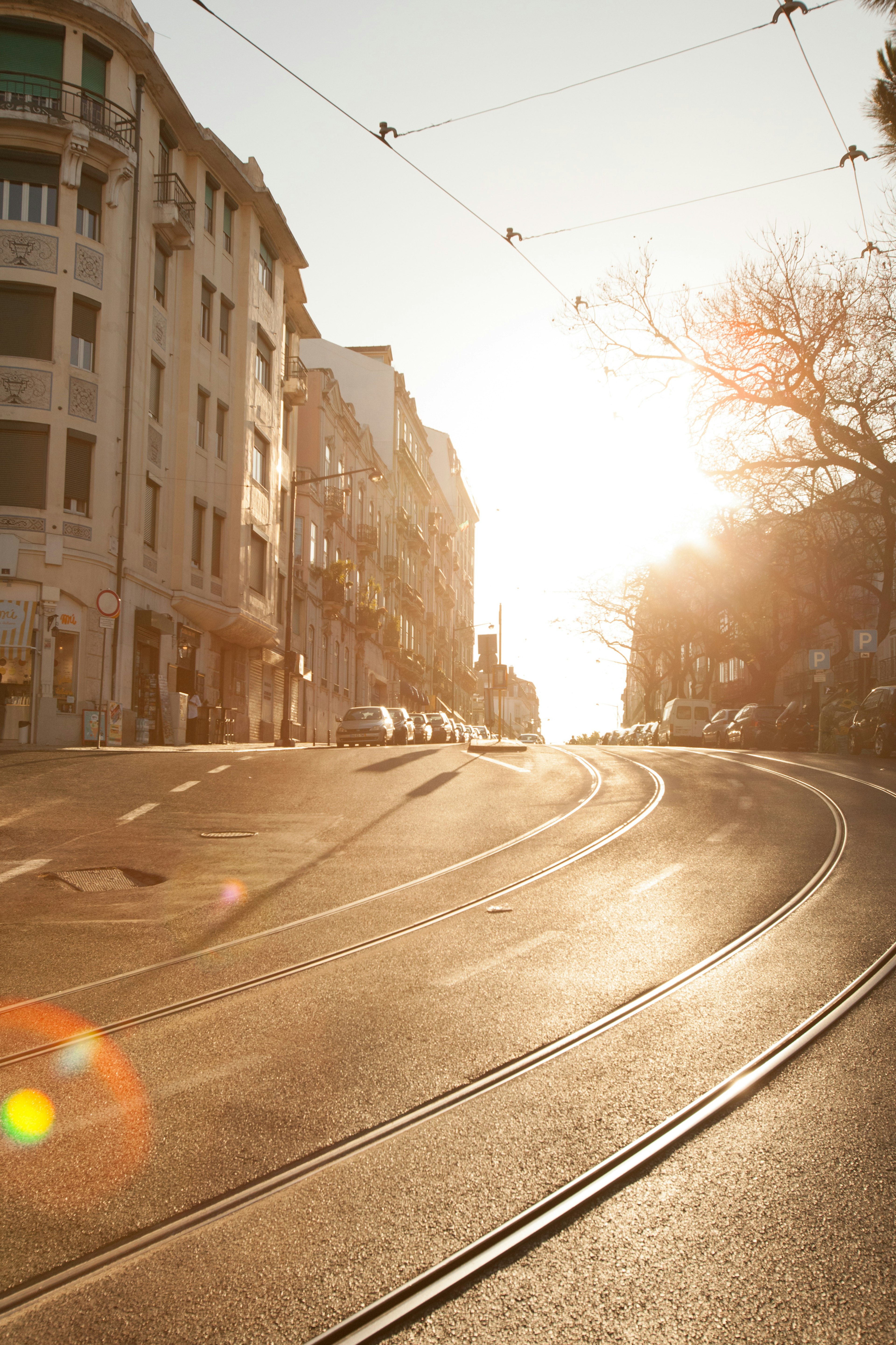 Escena de calle con el sol poniéndose sobre rieles de tranvía curvos