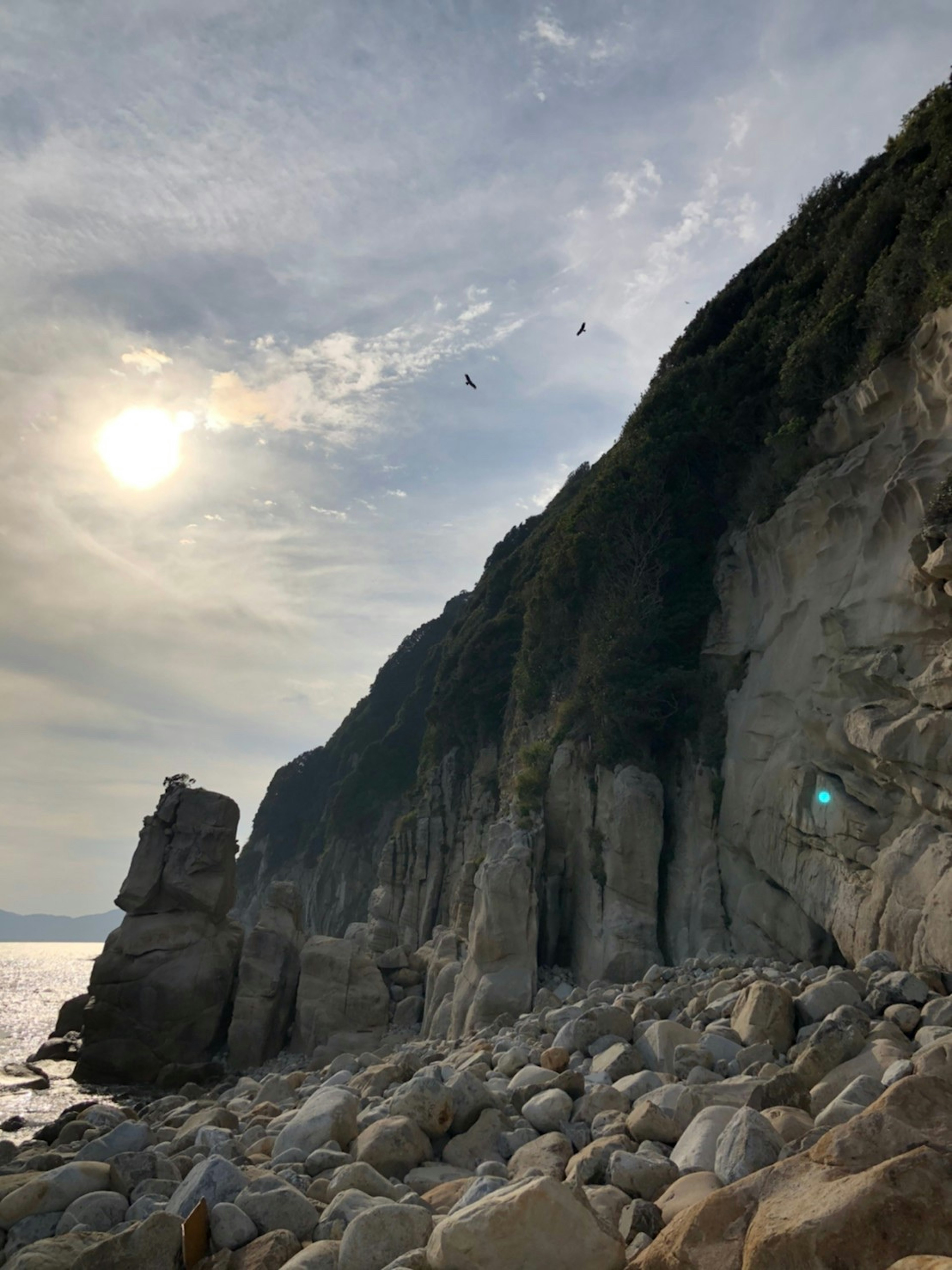 Scène côtière avec des falaises rocheuses et un soleil brillant dans le ciel