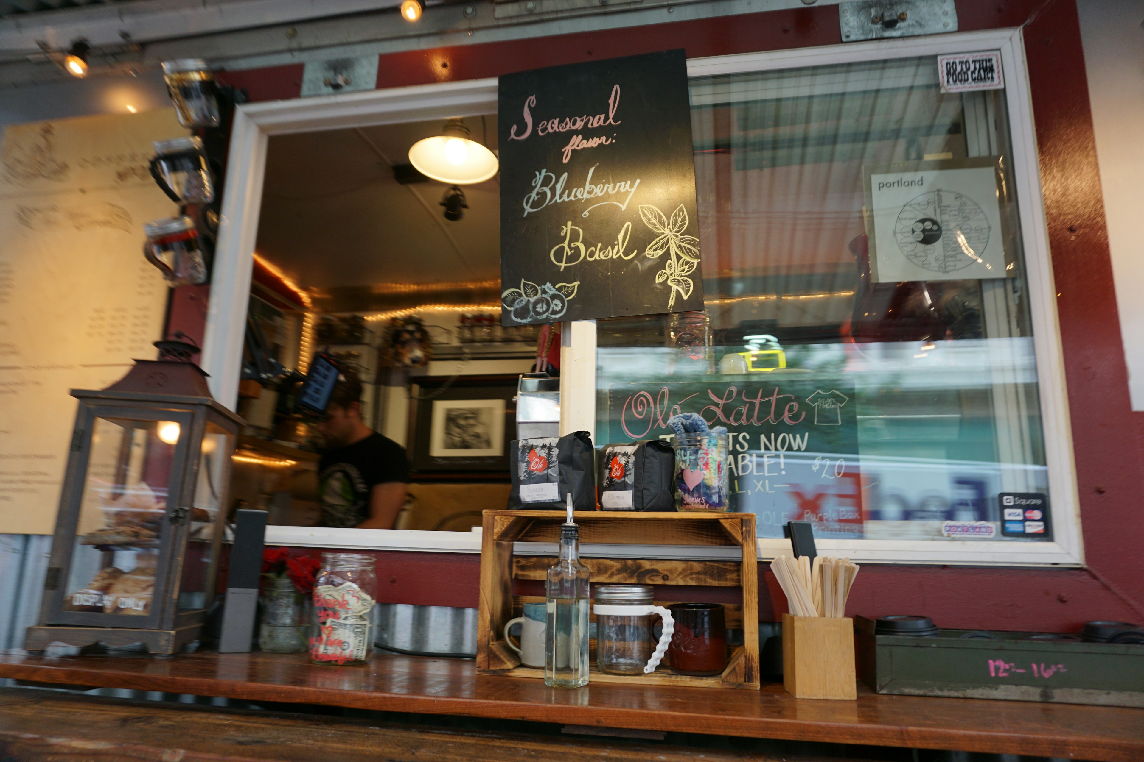 Cafe window with a menu displayed and various drinks arranged