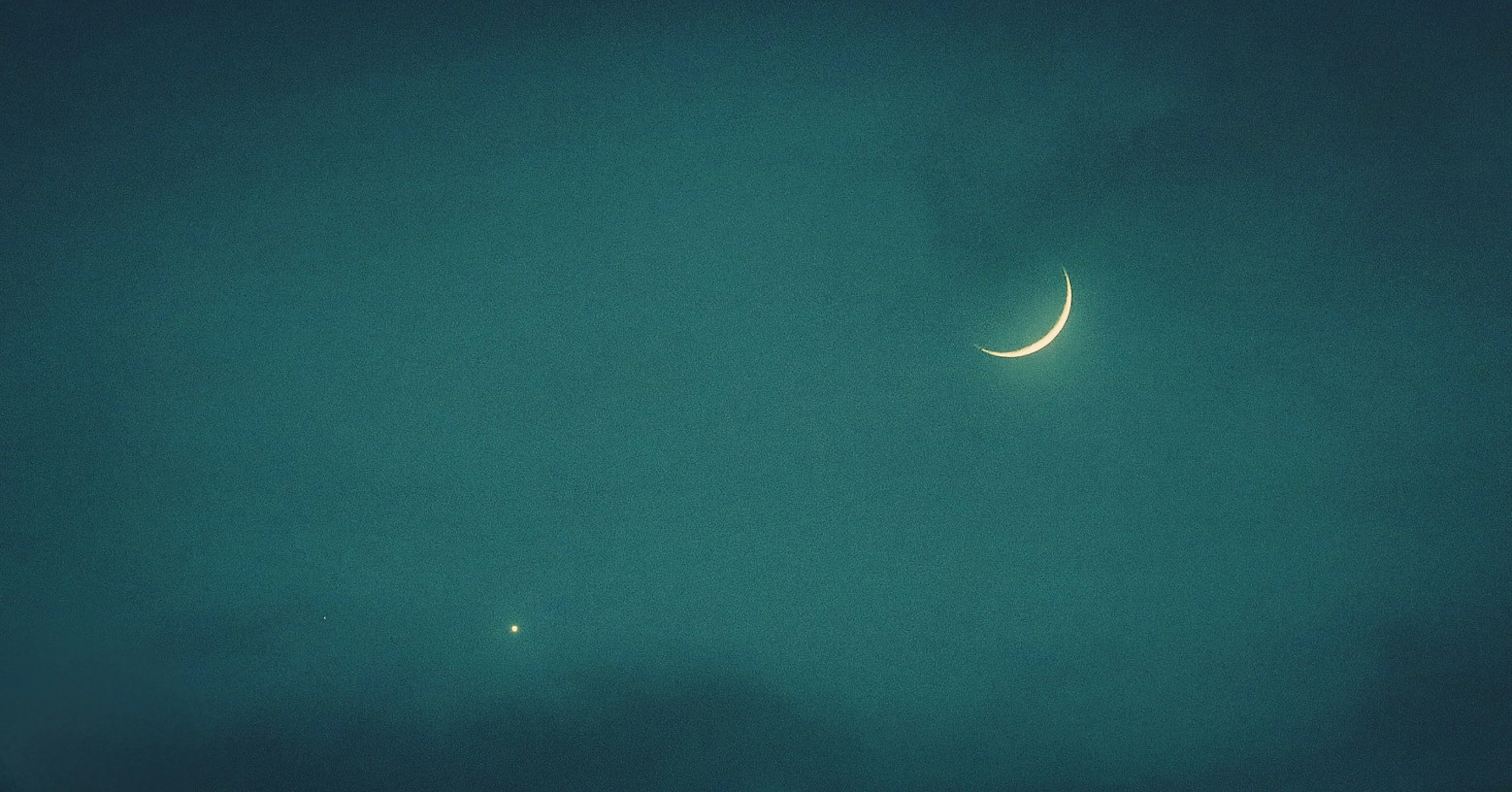 Un mince croissant de lune et une étoile brillante dans un ciel nocturne bleu