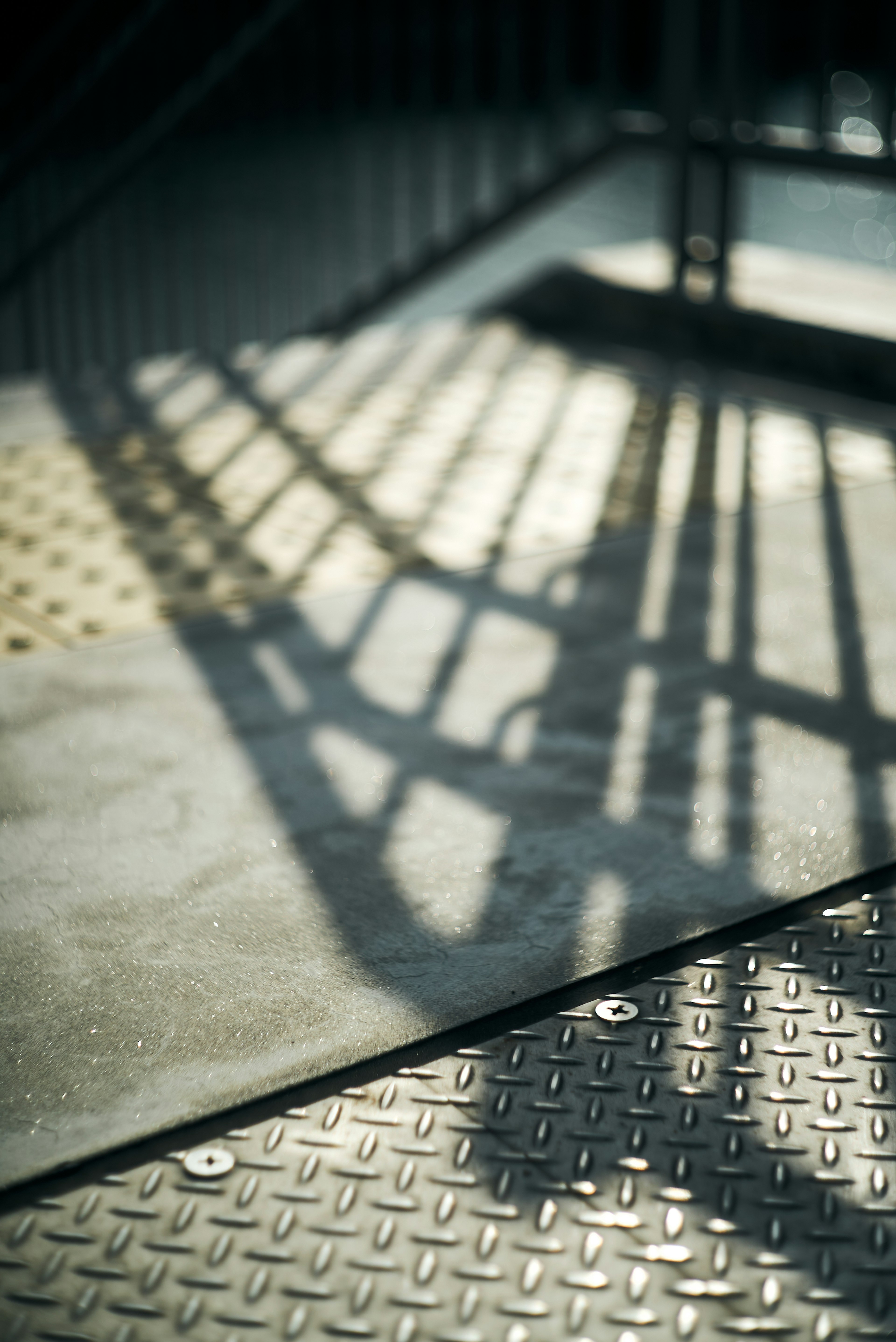 Shadows of stairs cast on textured floor with metallic surface