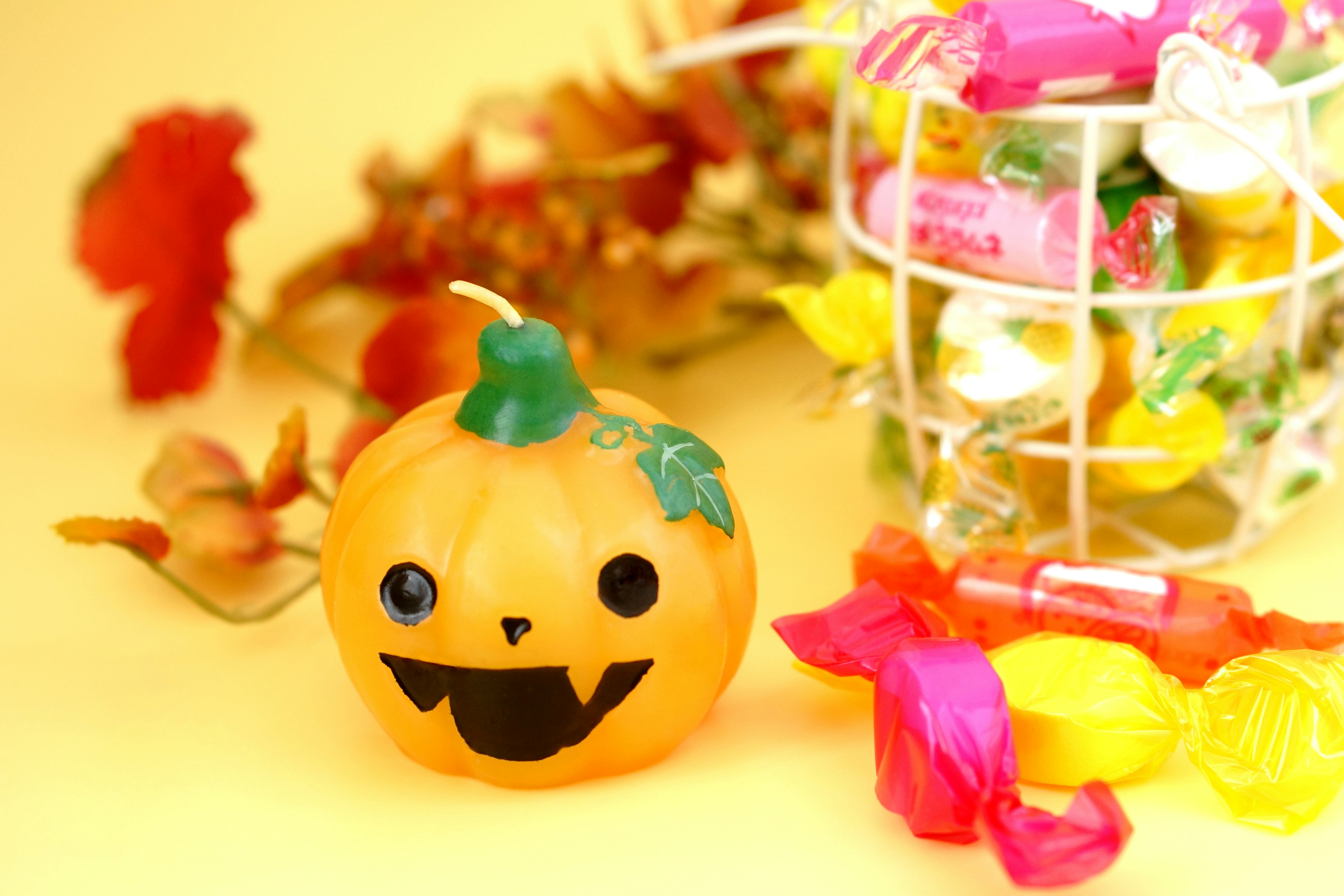 A smiling jack-o'-lantern on a yellow background with colorful candies