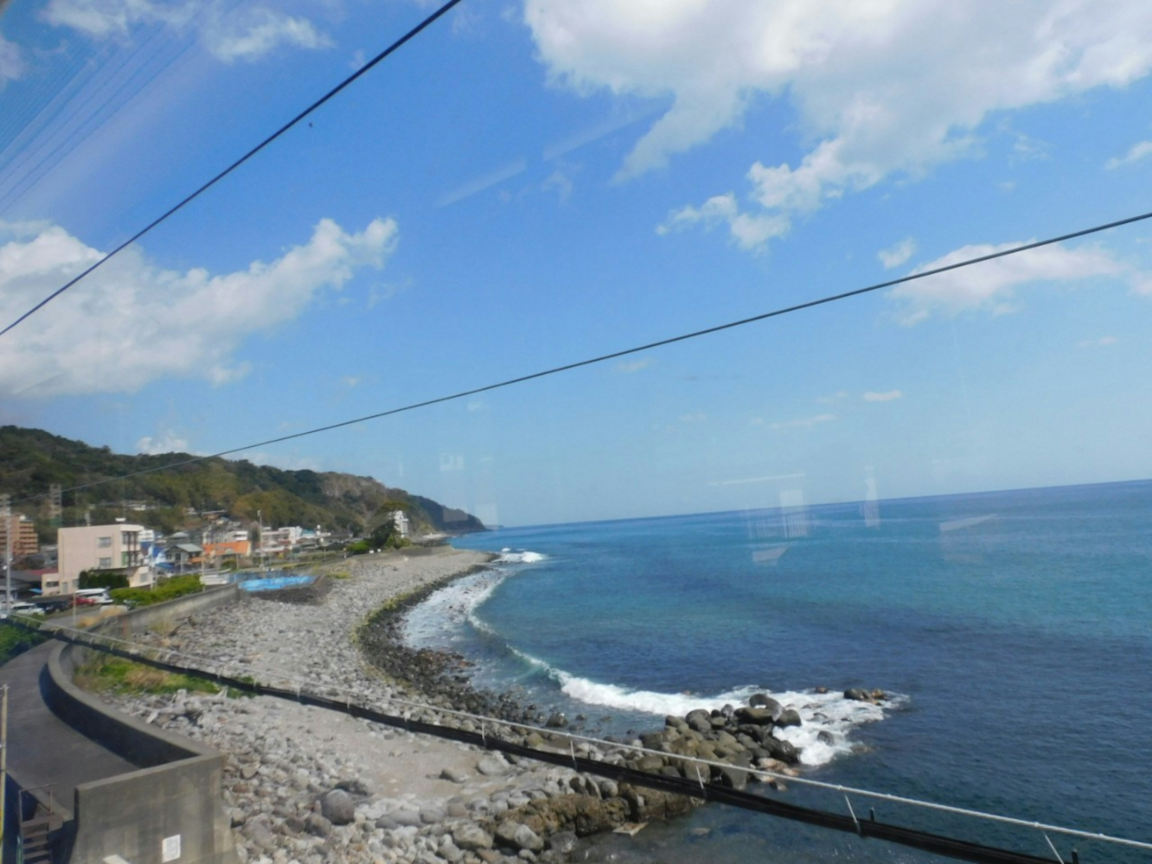 青い海と白い波が打ち寄せる浜辺の風景 鉄道の車窓からの眺め