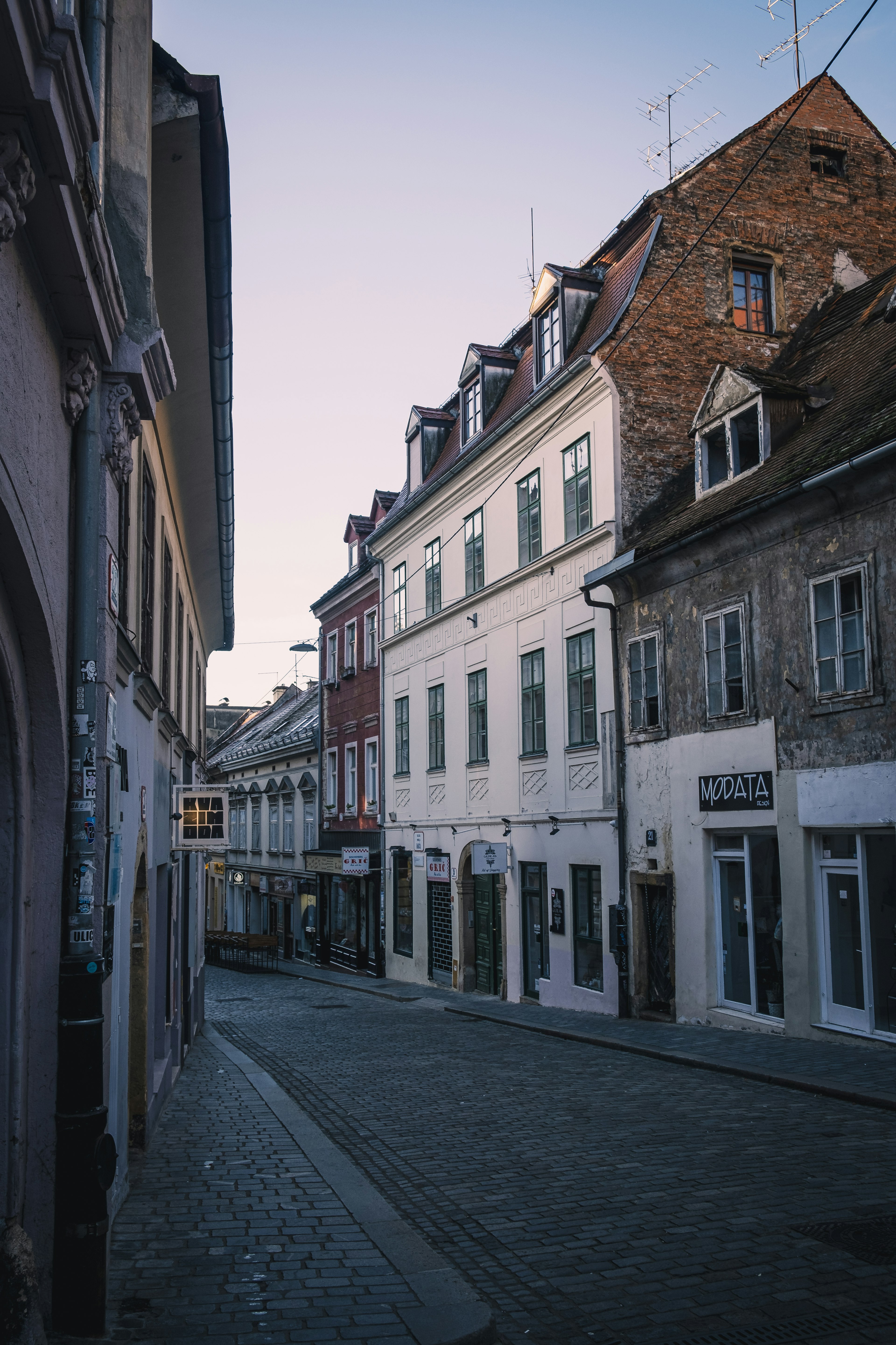 Ruhige Straße gesäumt von alten Gebäuden und Dämmerungshimmel