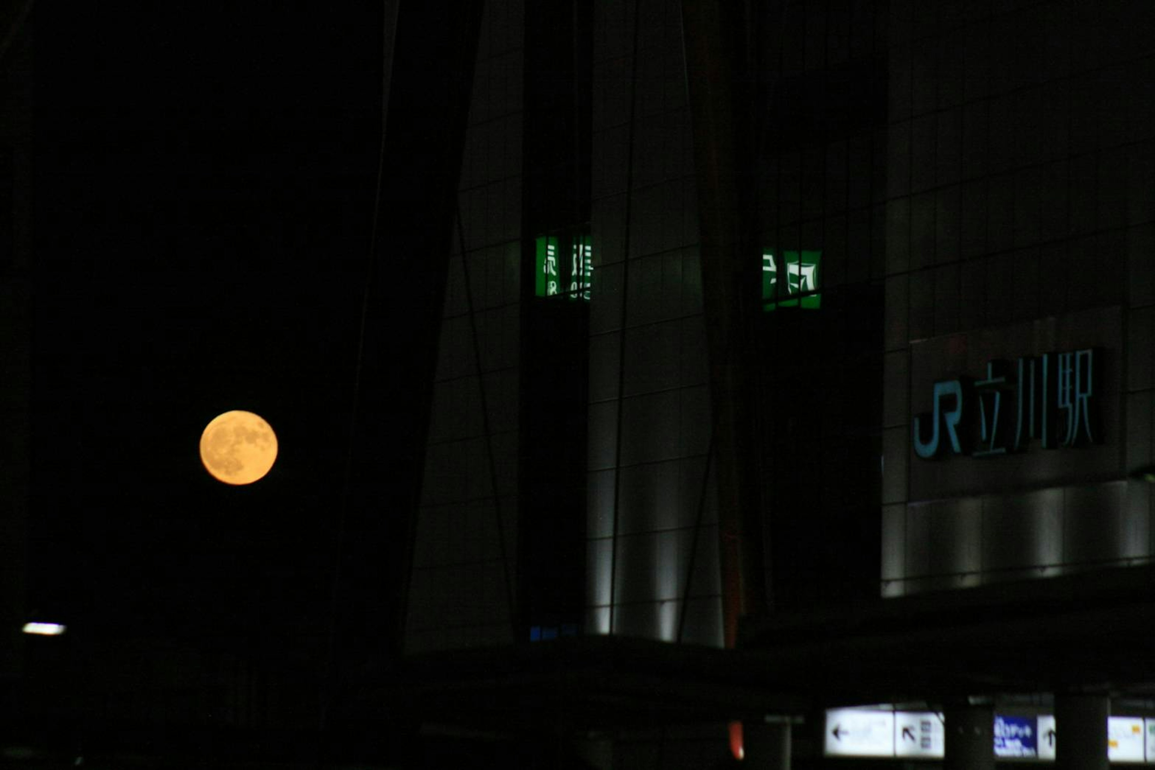 Luna brillante nel cielo notturno con insegna di un edificio vicino