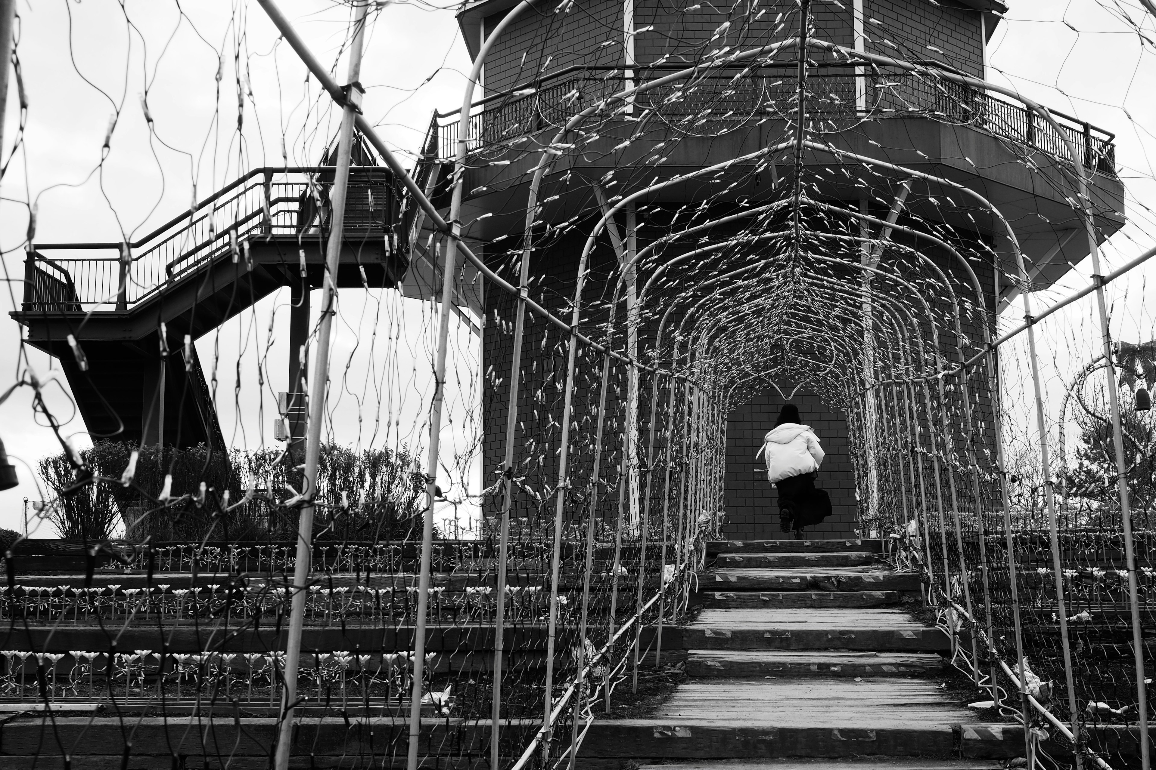 Una persona caminando a través de un túnel de red que conduce a una torre en blanco y negro