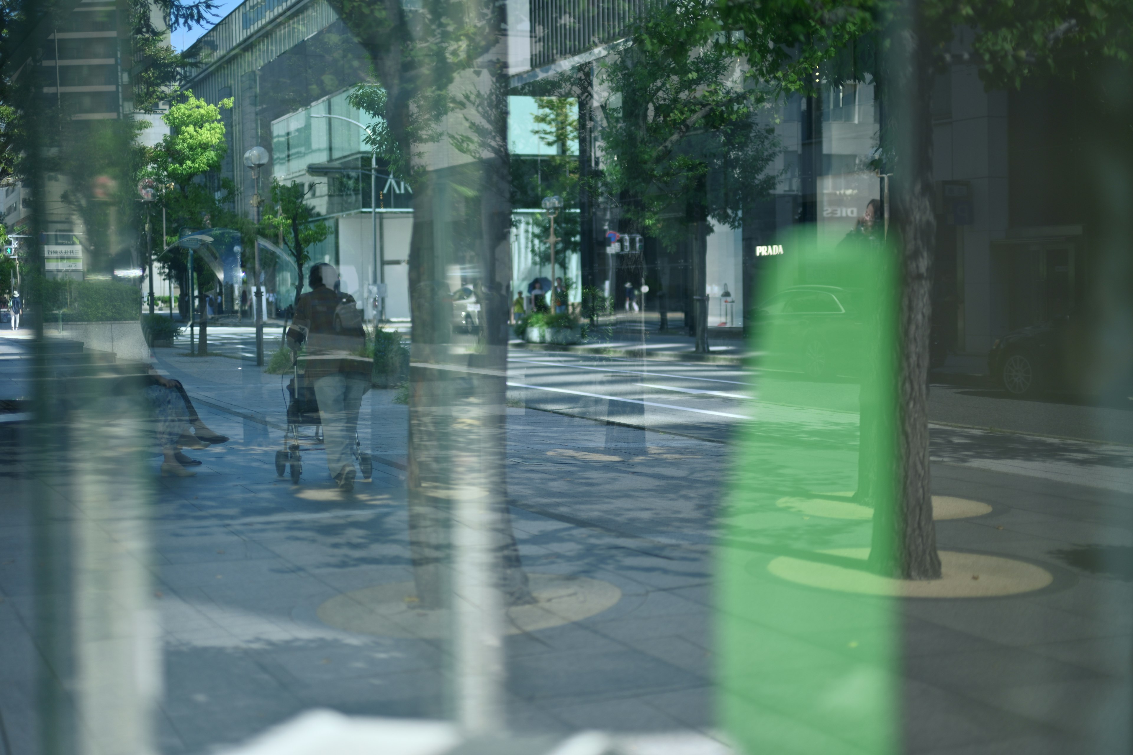 Urban scene with a green object reflection people and buildings in the background