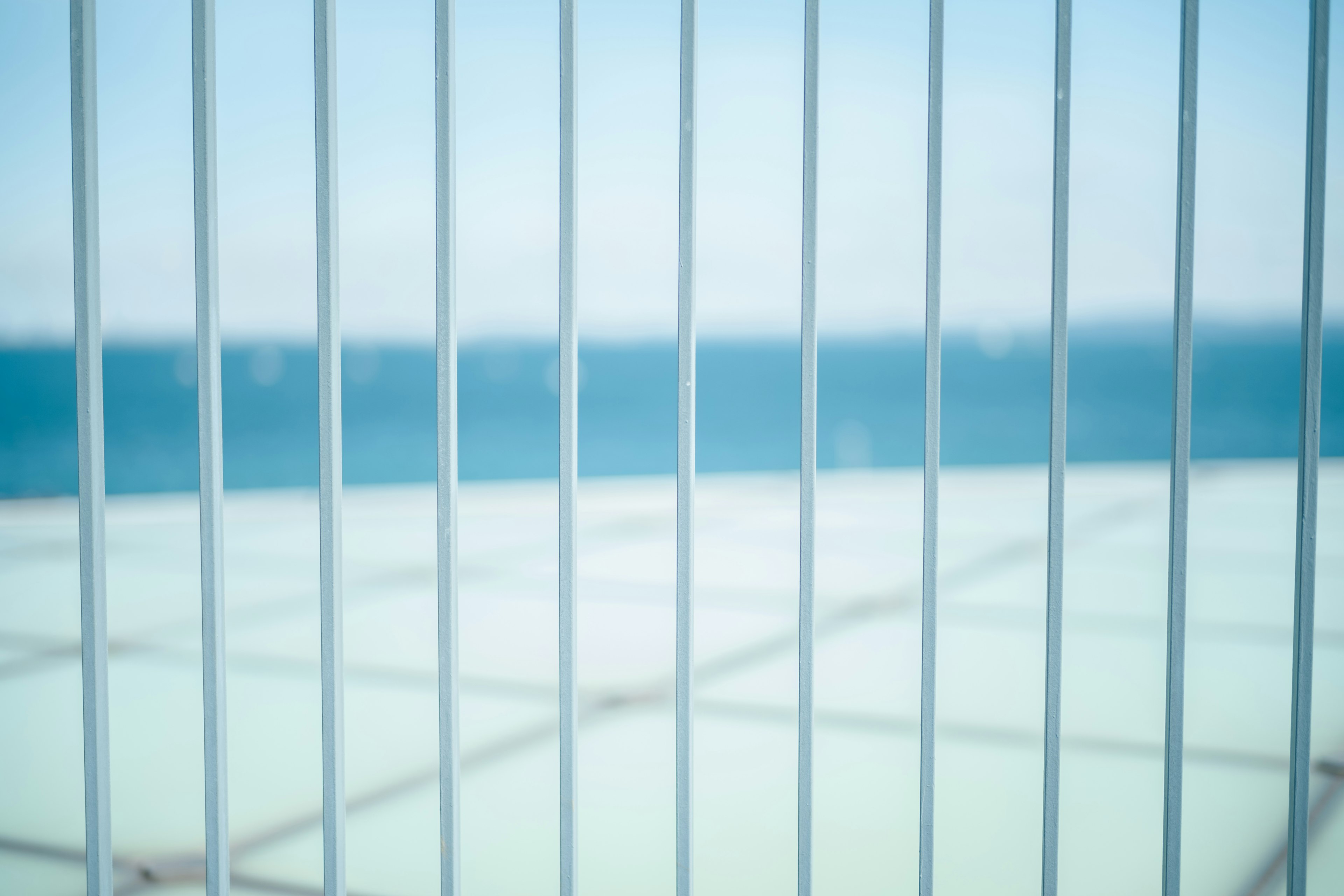 Close-up of a white fence with a blue ocean background