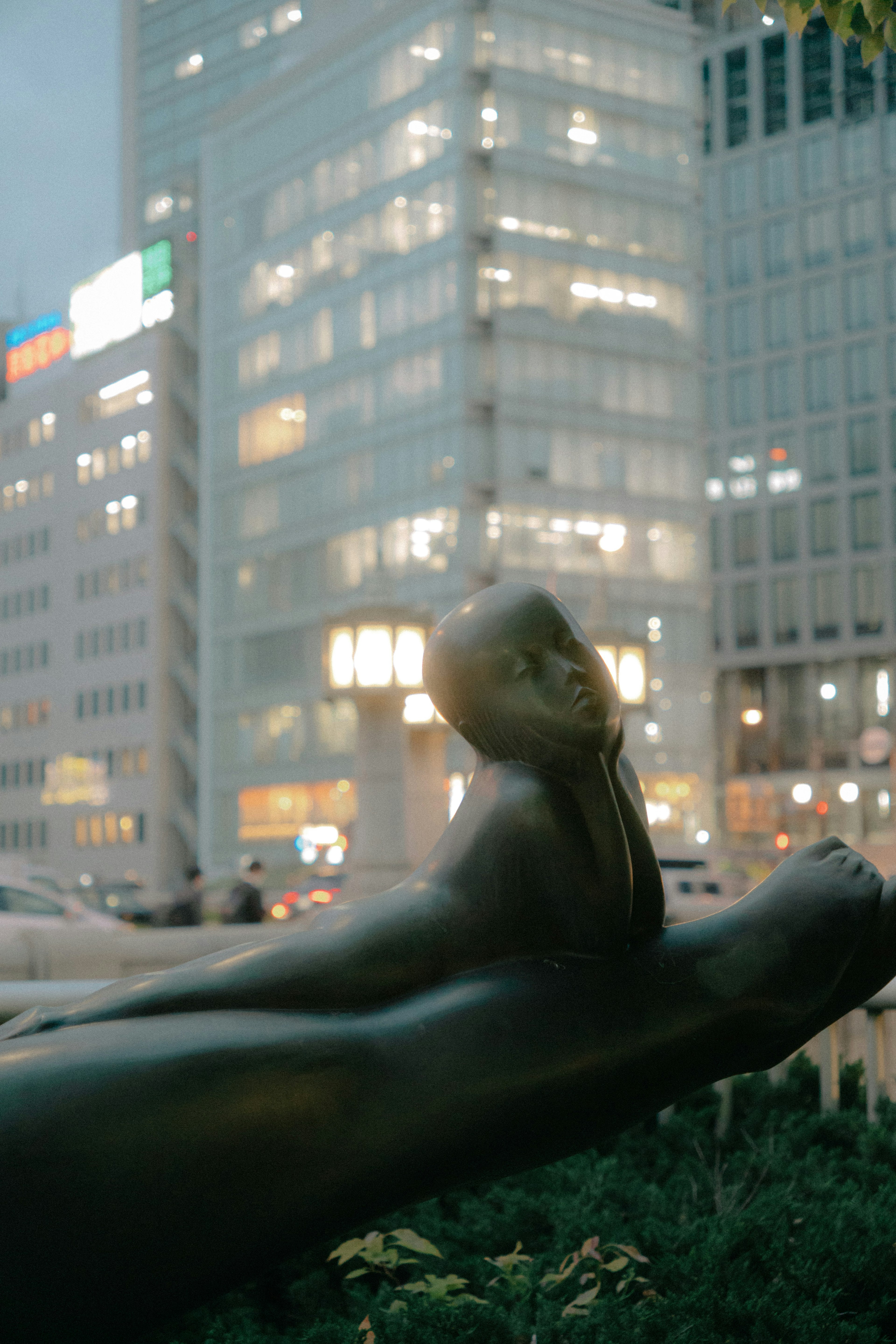 都市の風景にあるモダンな彫刻とビルの明かり