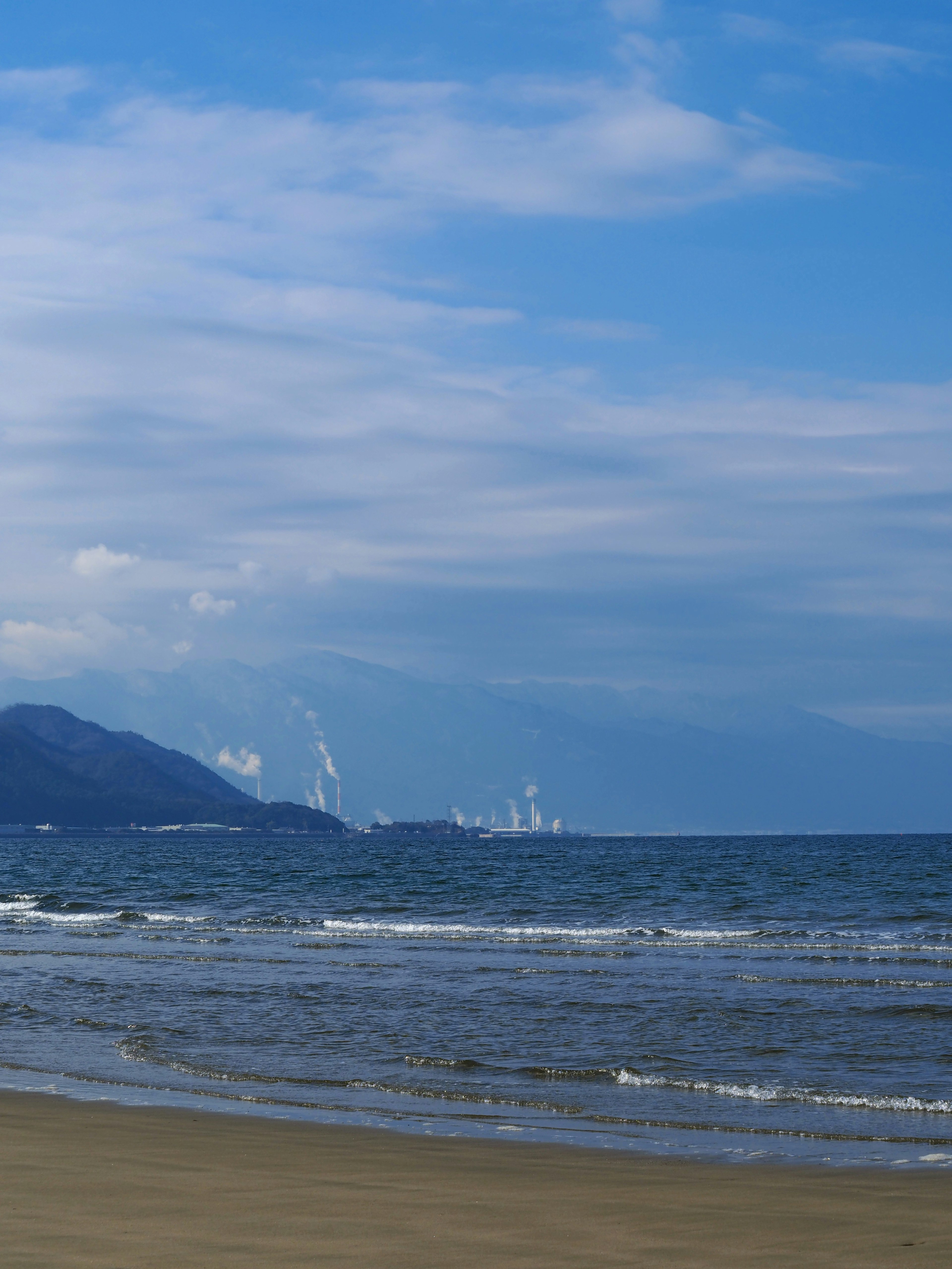 Pemandangan indah laut biru tenang dan langit dengan gelombang lembut di pantai