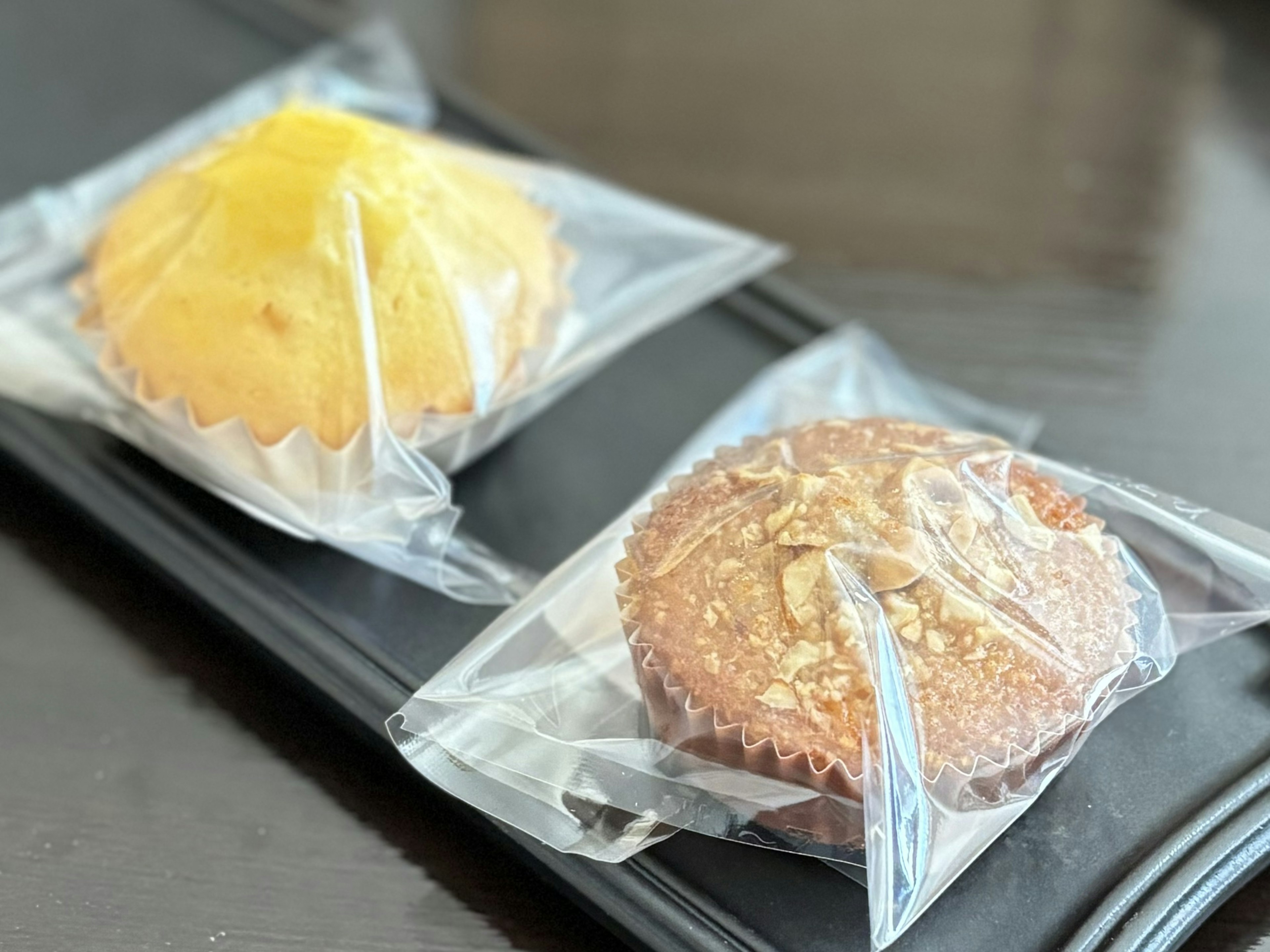 Two wrapped muffins placed on a black plate