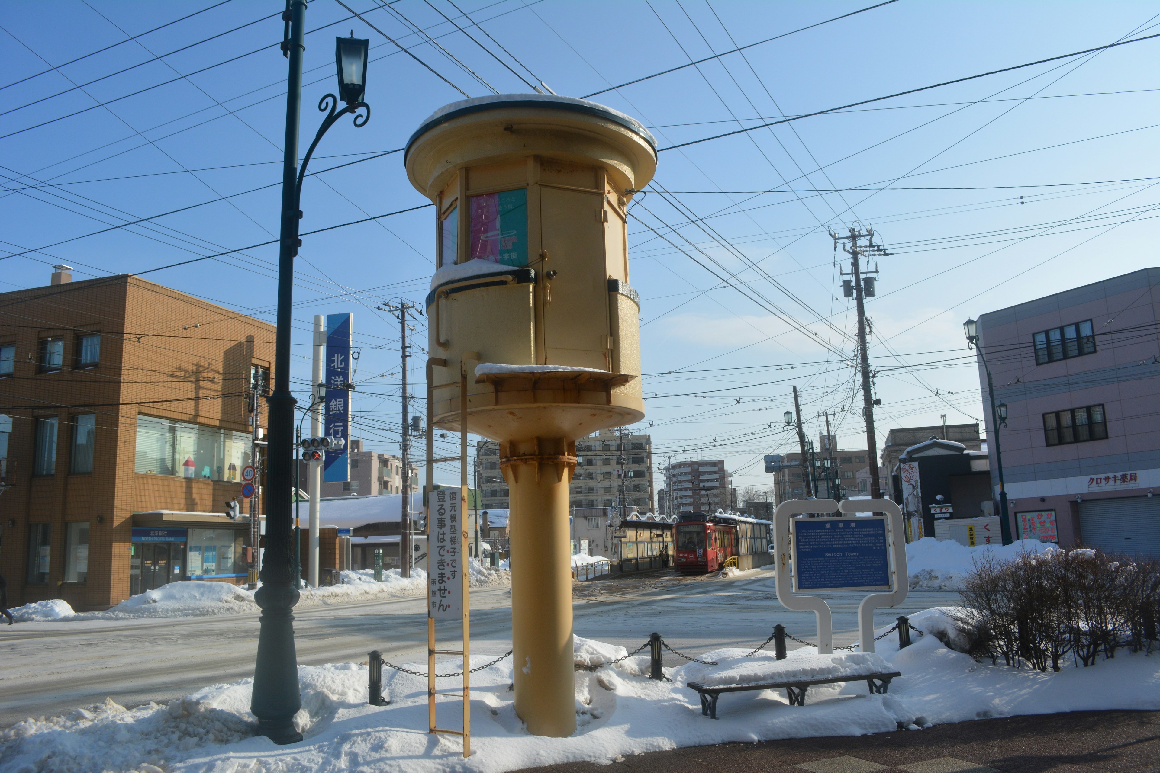 雪に覆われた街角に立つ黄色い電話ボックスと周囲の風景