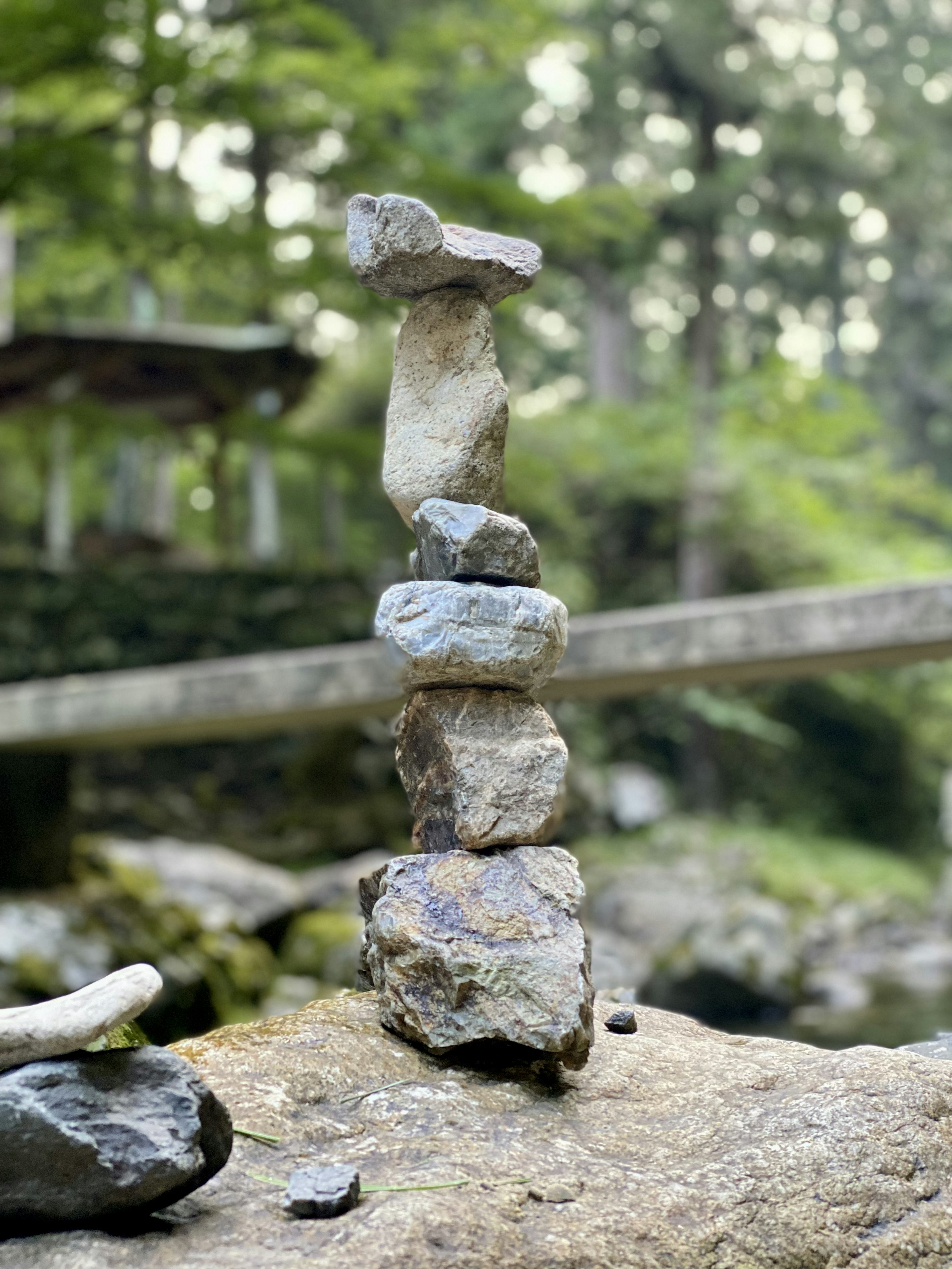 Stacked stone sculpture in a natural setting surrounded by greenery