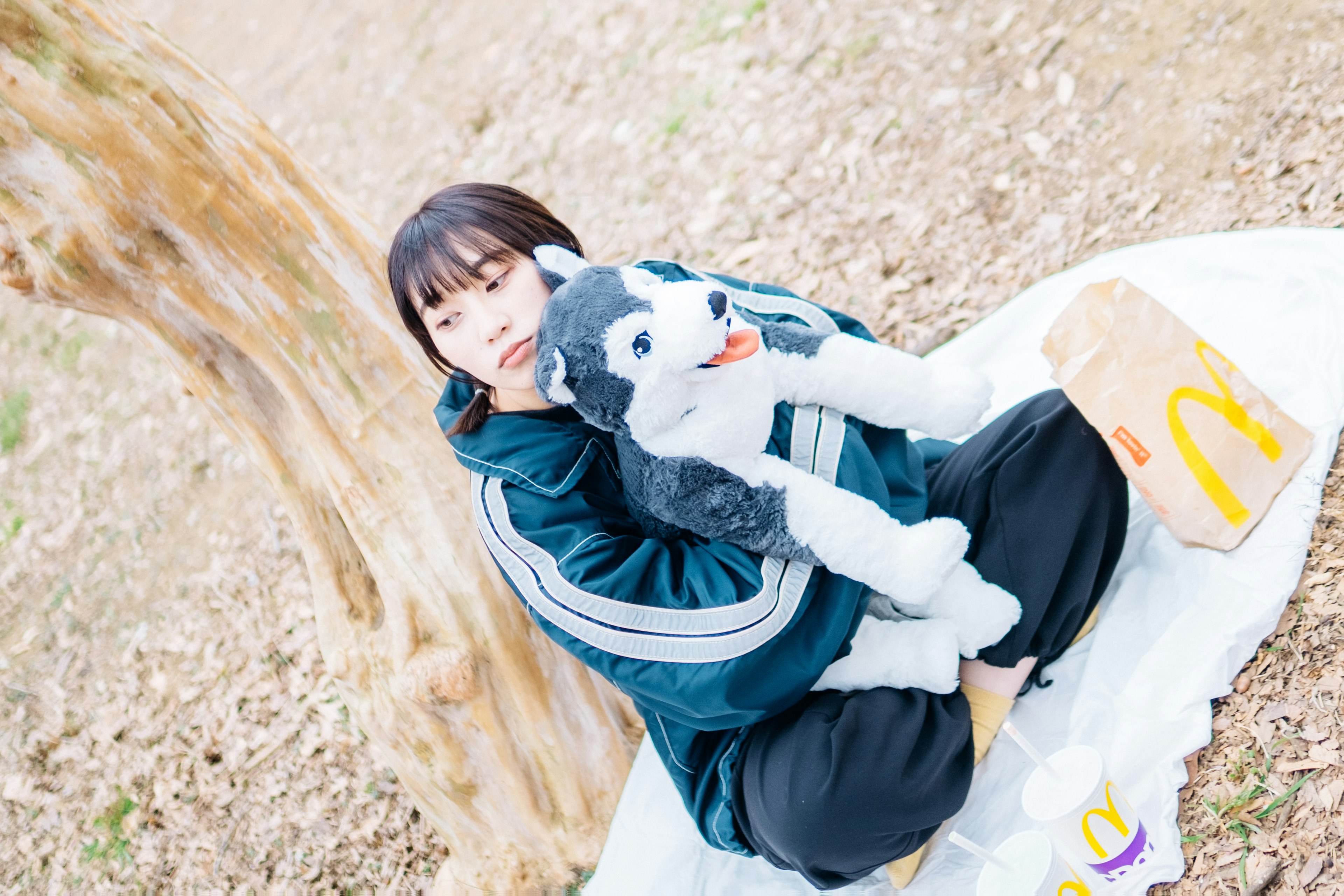 A woman sitting in a park holding a plush dog