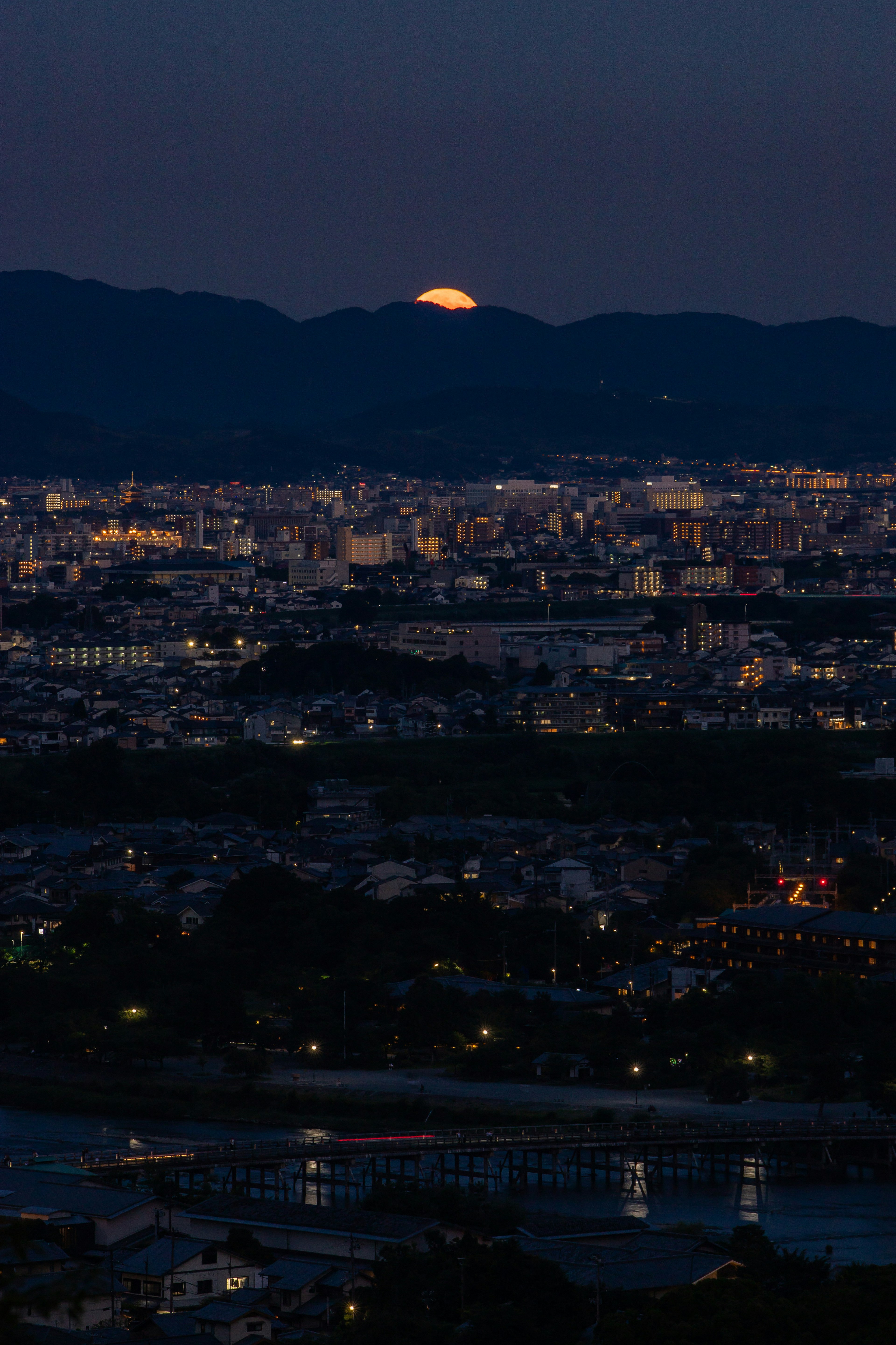 Vista nocturna con una luna saliente sobre las montañas