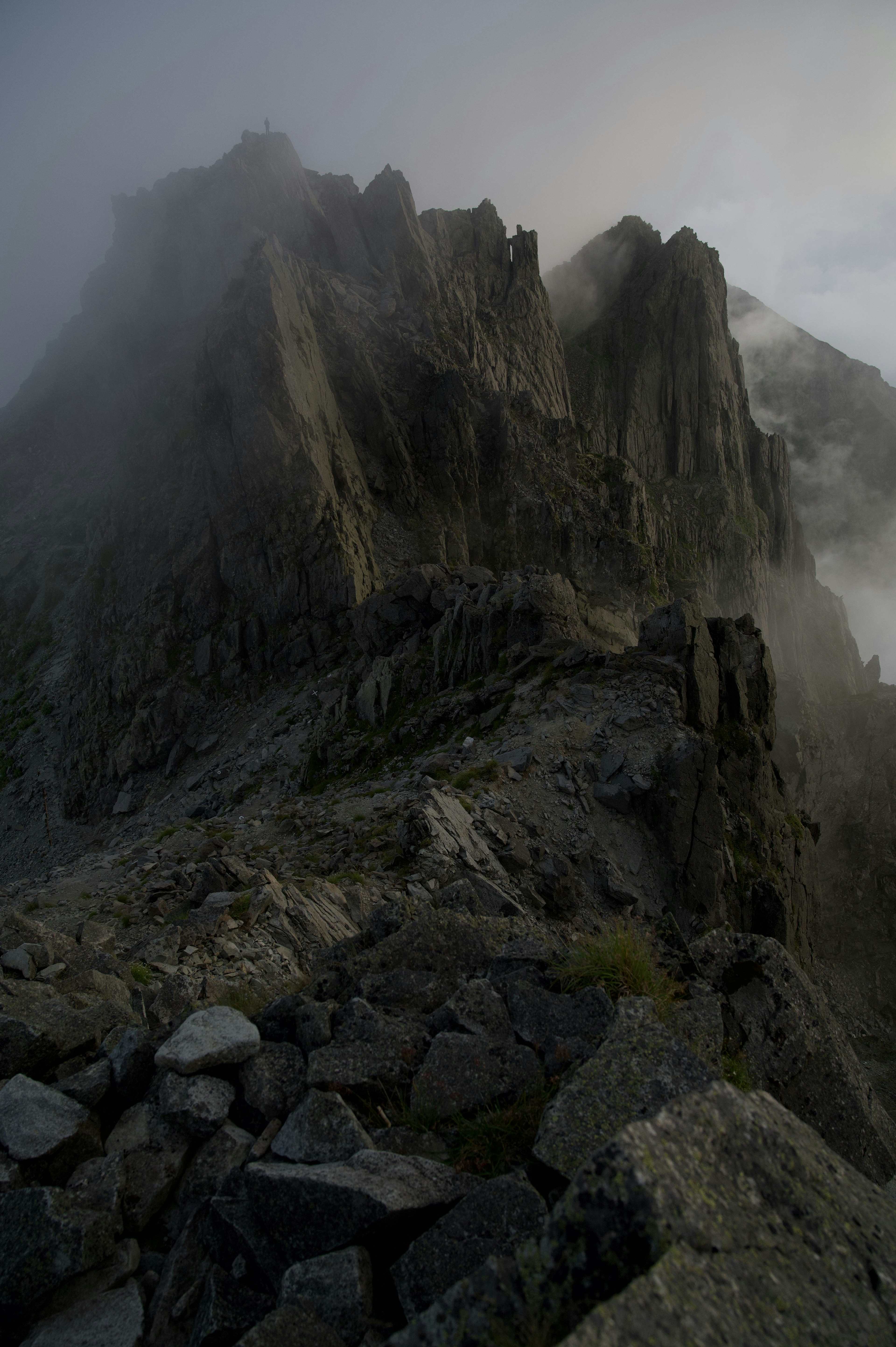 Vista nebbiosa di una cima montuosa impervia e di un terreno roccioso